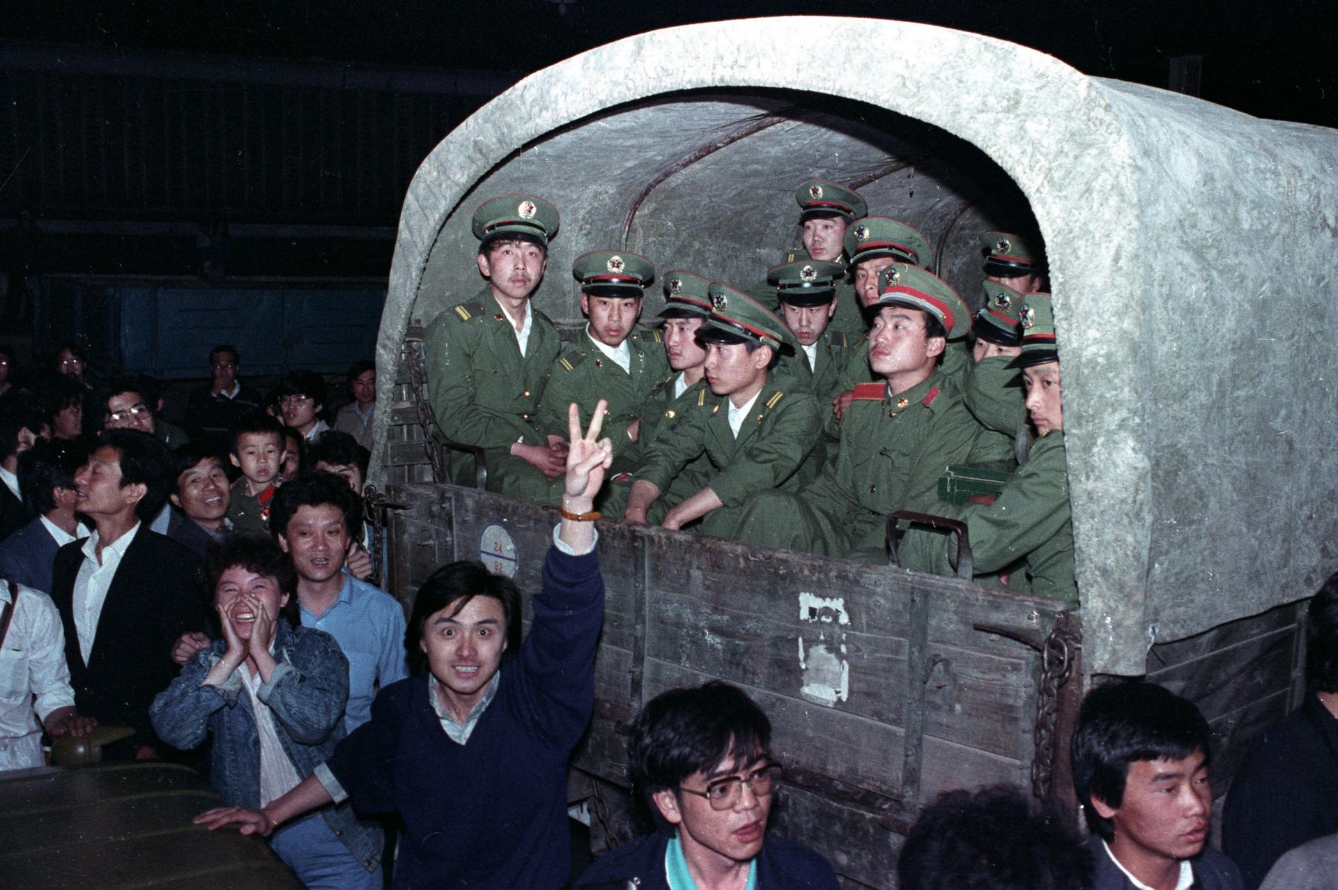 At night a group of students surround a military vehicle. 
