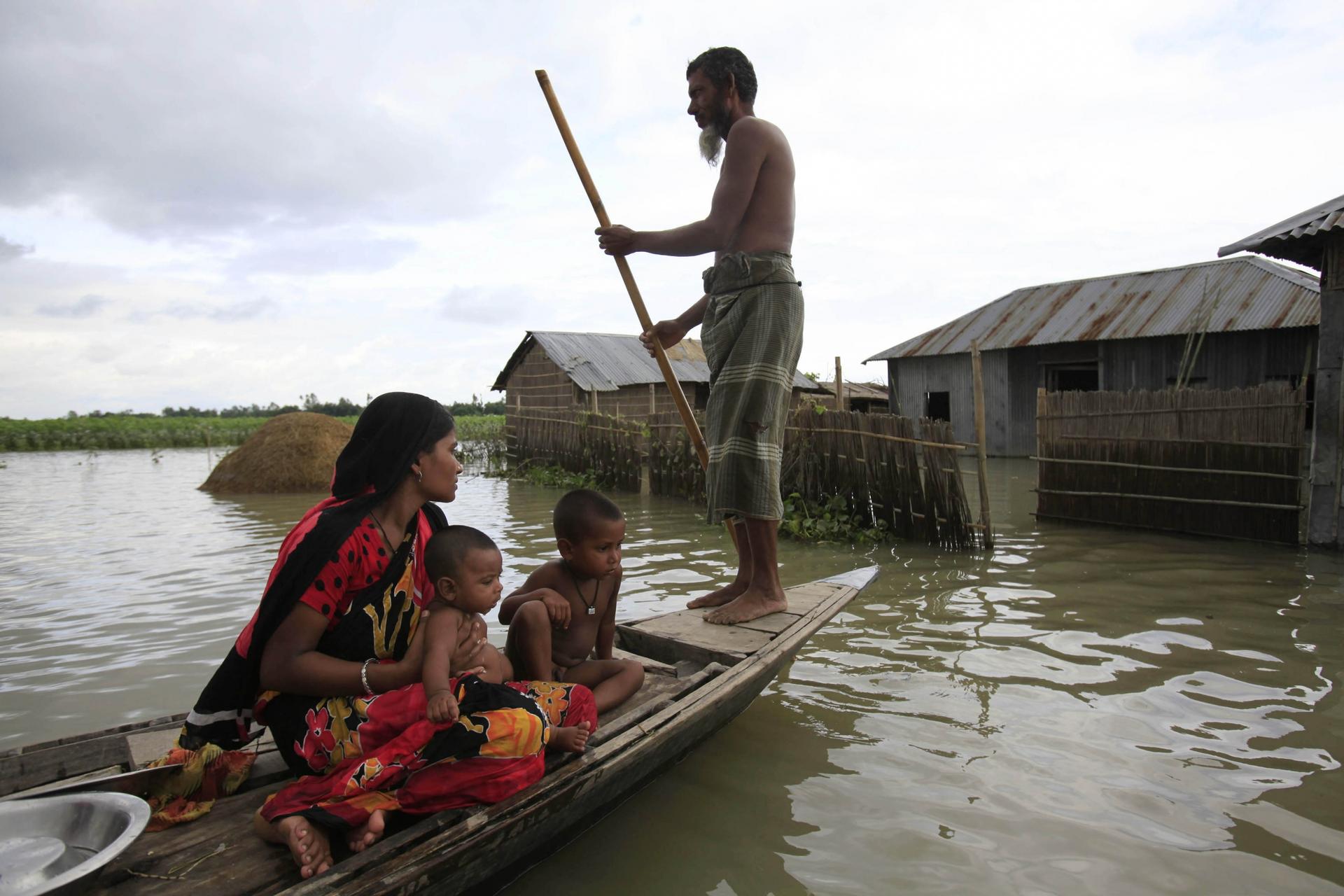 A family sits on a small boat in a flooded village. 