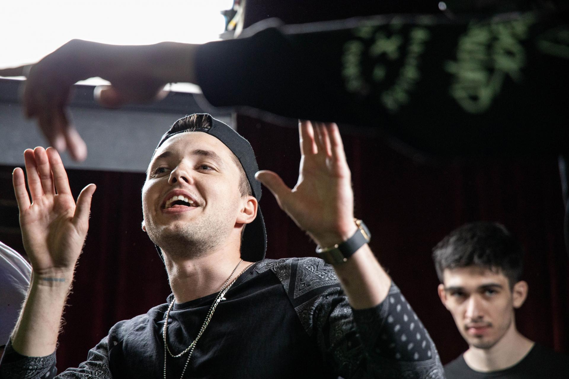 A rapper raises his hands at a crowd. 