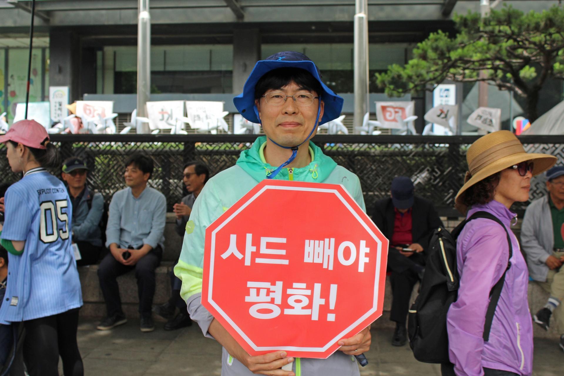 A man holds red protest sign encouraging engagement between US and NK. 