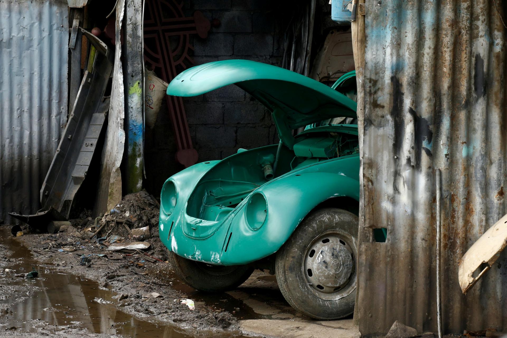 The front end of a Volkswagen Beetle is shown sticking out from a metal garage.