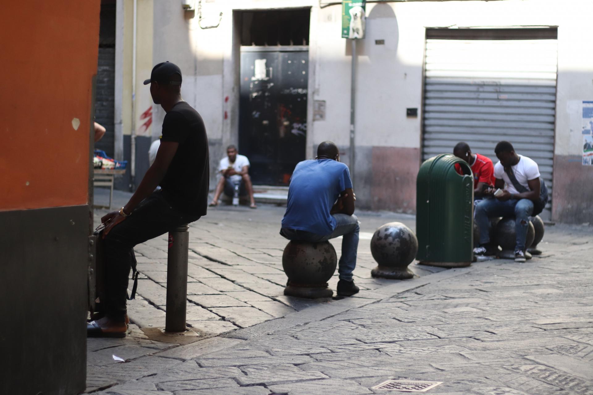 asylum-seekers sit in the street idly