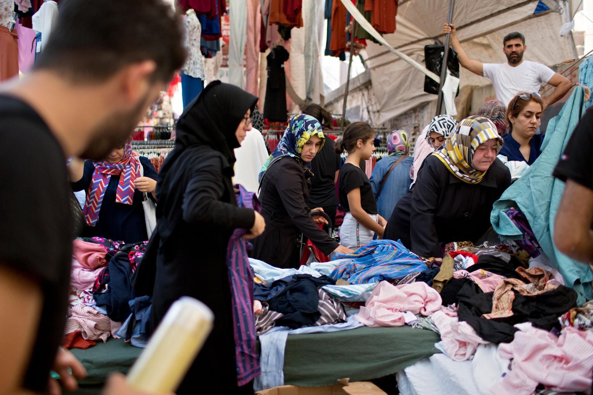 Several women wearing head shalls are show shopping at a market.
