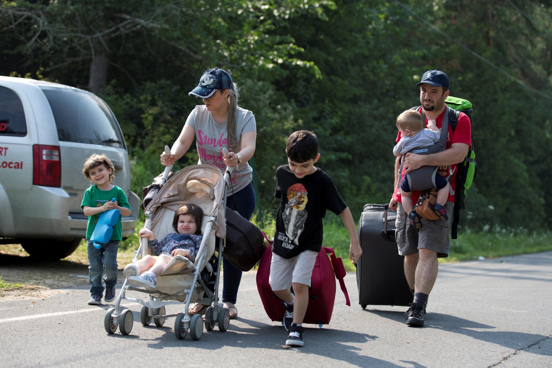 A family of four pushes stroller across a road 