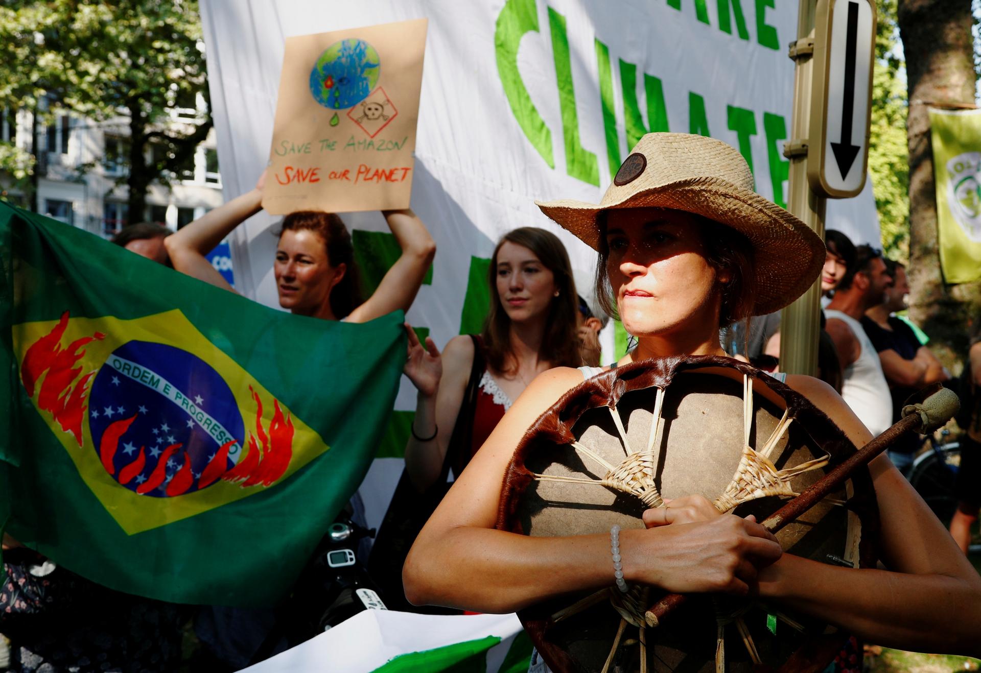 Activists with signs and Brazilian flags march through the streets. 