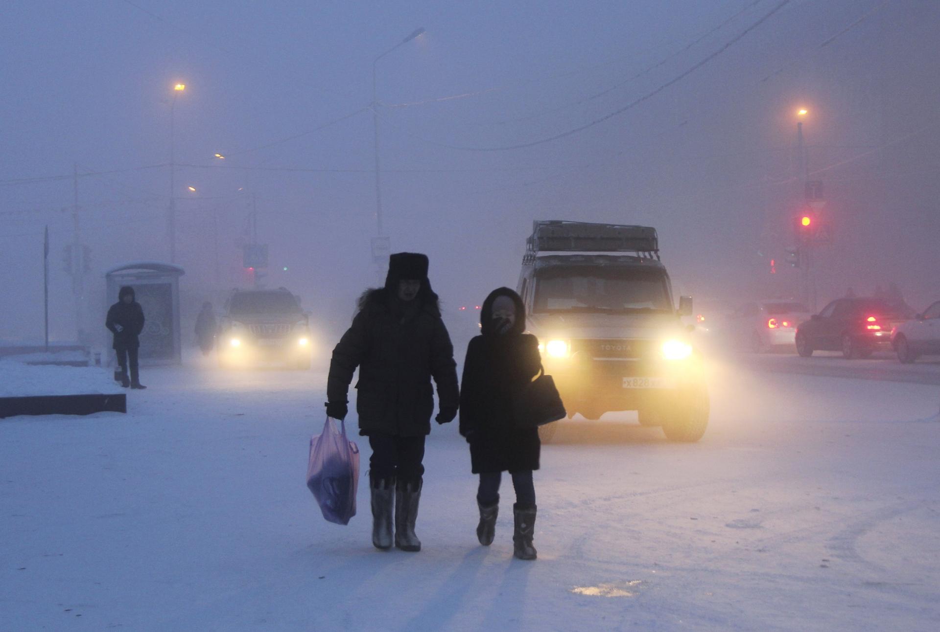 Two people walk in a snowy street scene.