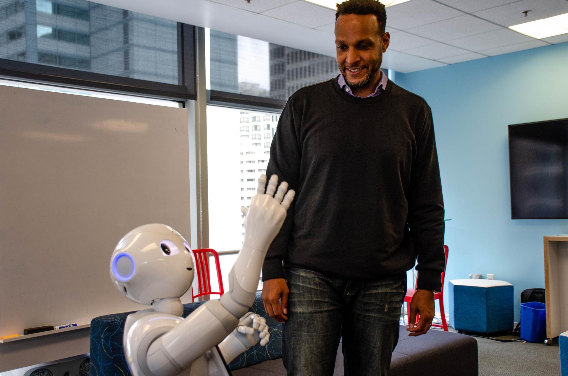 Softbank Robotics’ Kass Dawson, who stands 6’5” interacts with Pepper, the robot. Dawson says Pepper was designed to be four-feet-tall to make it more “approachable.”