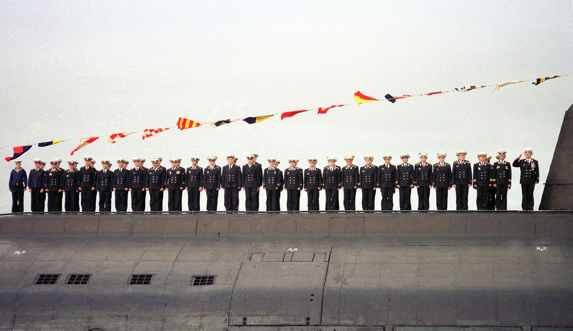 Sailors stand in a line atop their submarine in uniform