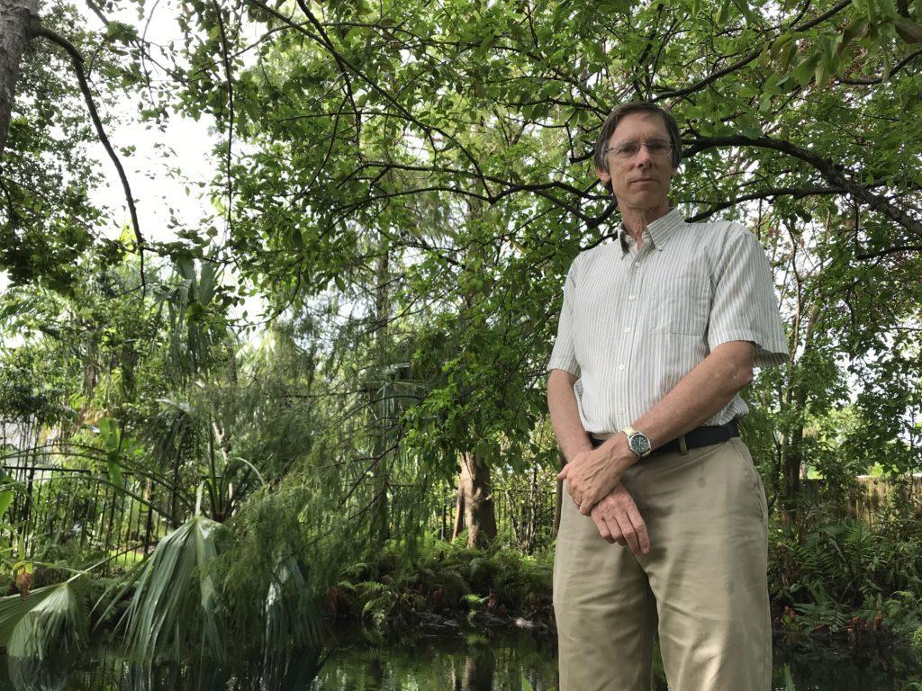 A portrait of Philip Stoddard, a biologist at Florida International University and mayor of South Miami, standing in his tree-filled backyard in 2017. 