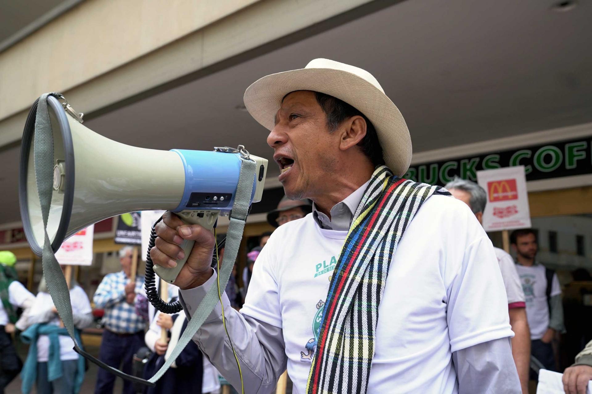 A man in a straw hat holds a megaphone outside a Starbucks coffee.