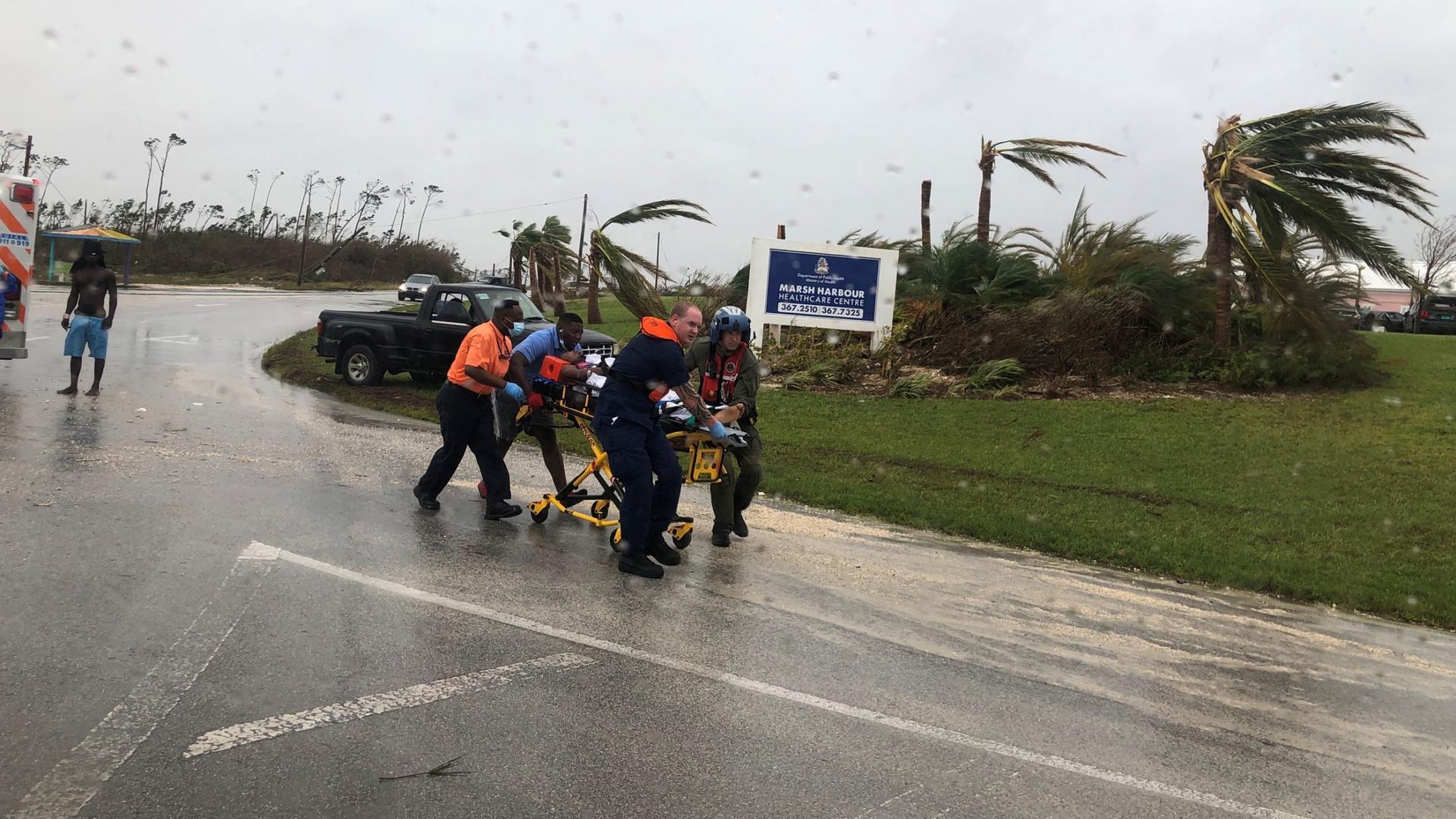 Four people run through a deserted street while pushing a guerney that's holding a patient during Hurricane Dorian.