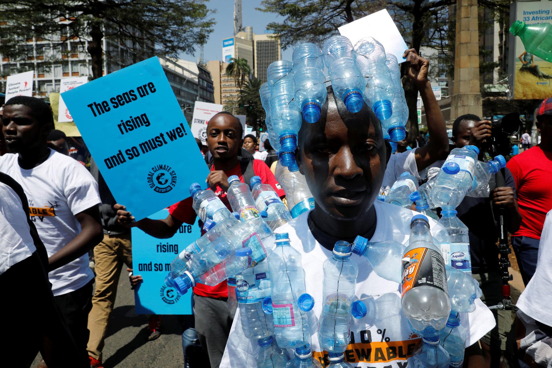 A man is shown with several empty plastic bottles attached to his shirt.