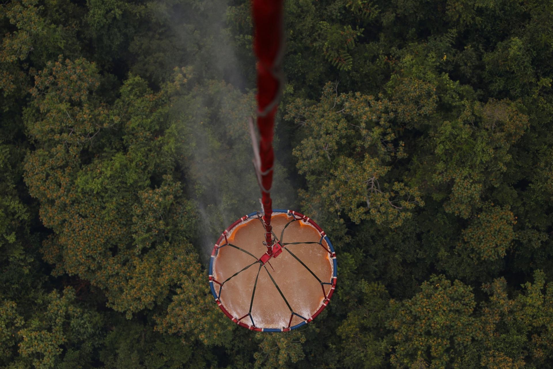 An ariel view is shown looking down at a large container of water with a forest down below.
