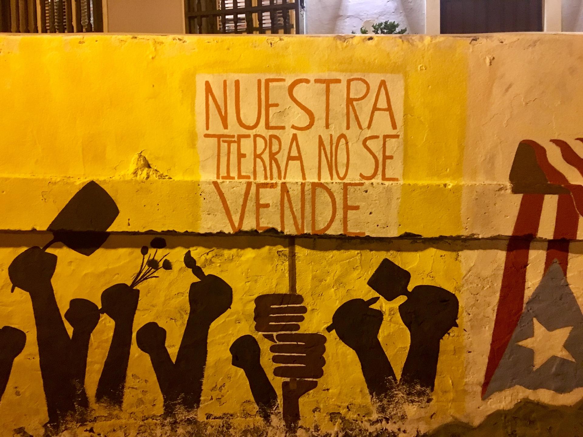 Our land is not for sale painted on a wall in Spanish with yellow paint