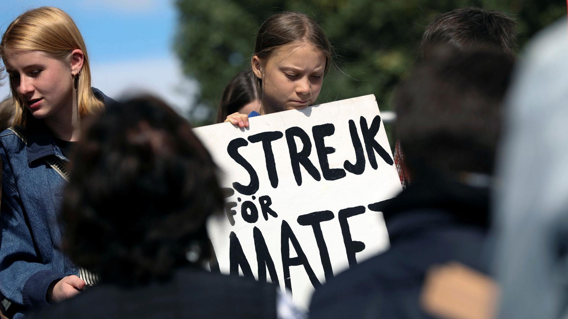Climate change environmental teen activist Greta Thunberg participates in a climate strike rally and looks down at a placard 