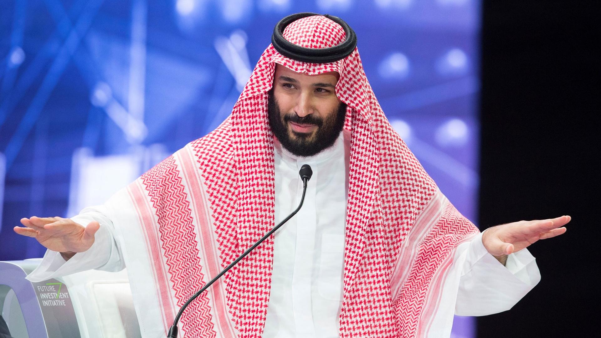 Crown Prince Mohammad bin Salman is picture with his hands outstretched, talking at a microphone