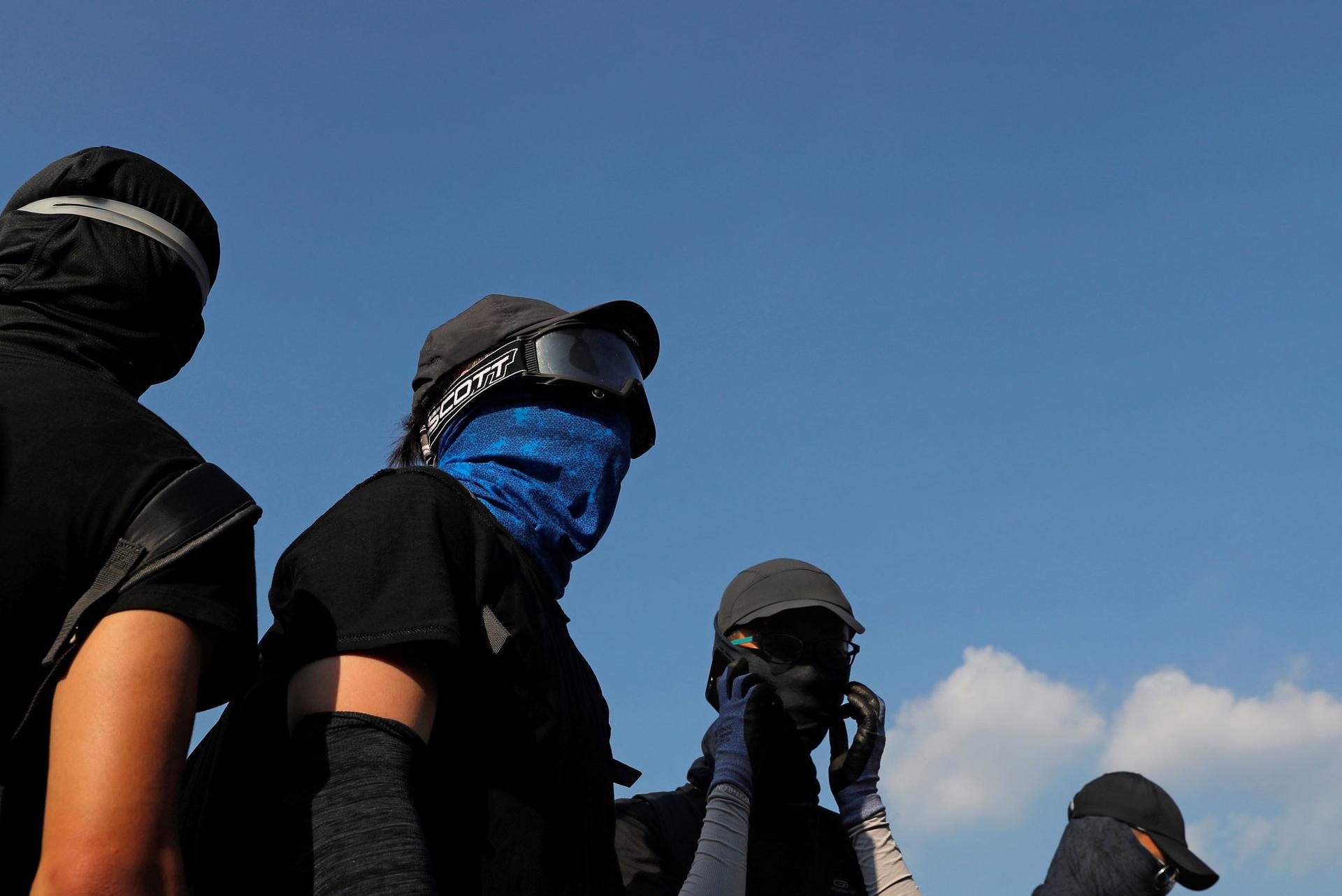 Several people are shown wearing face masks and goggles with a blue sky in the background.