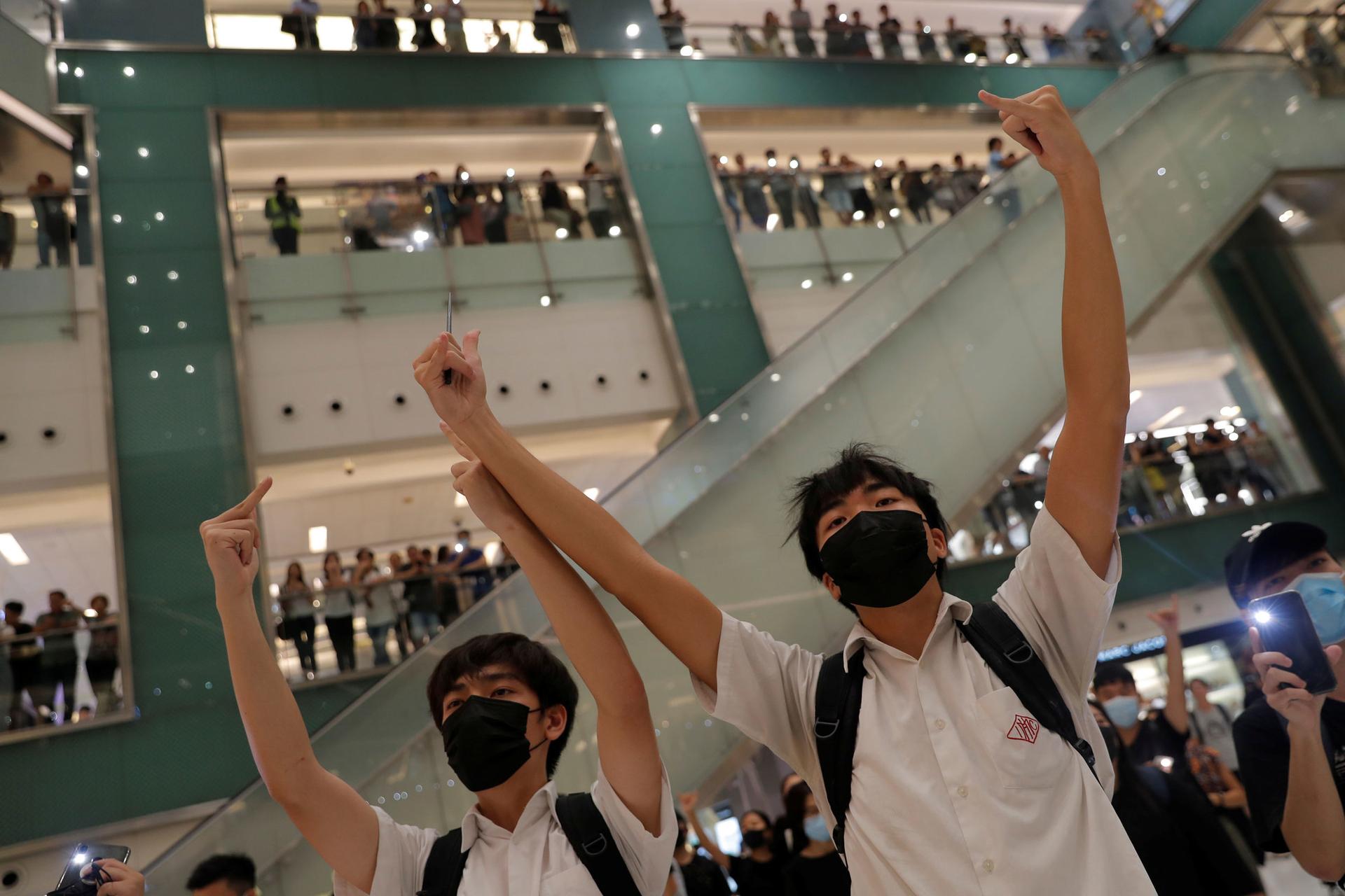 Two men are shown wearing back packs and black masks with their arms raised in the air gesturing.
