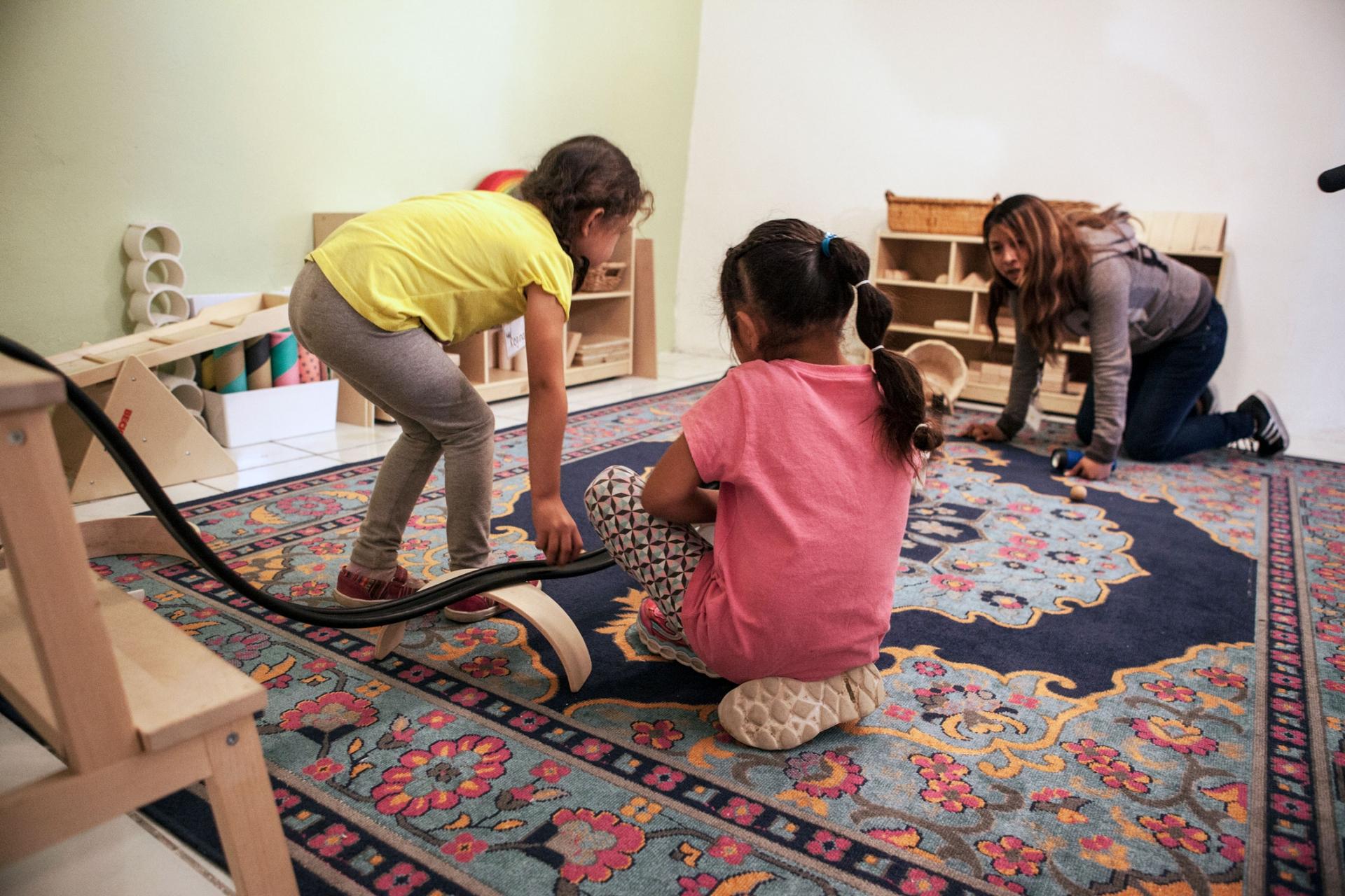 Two young girls are shown playing with a toy racing track.