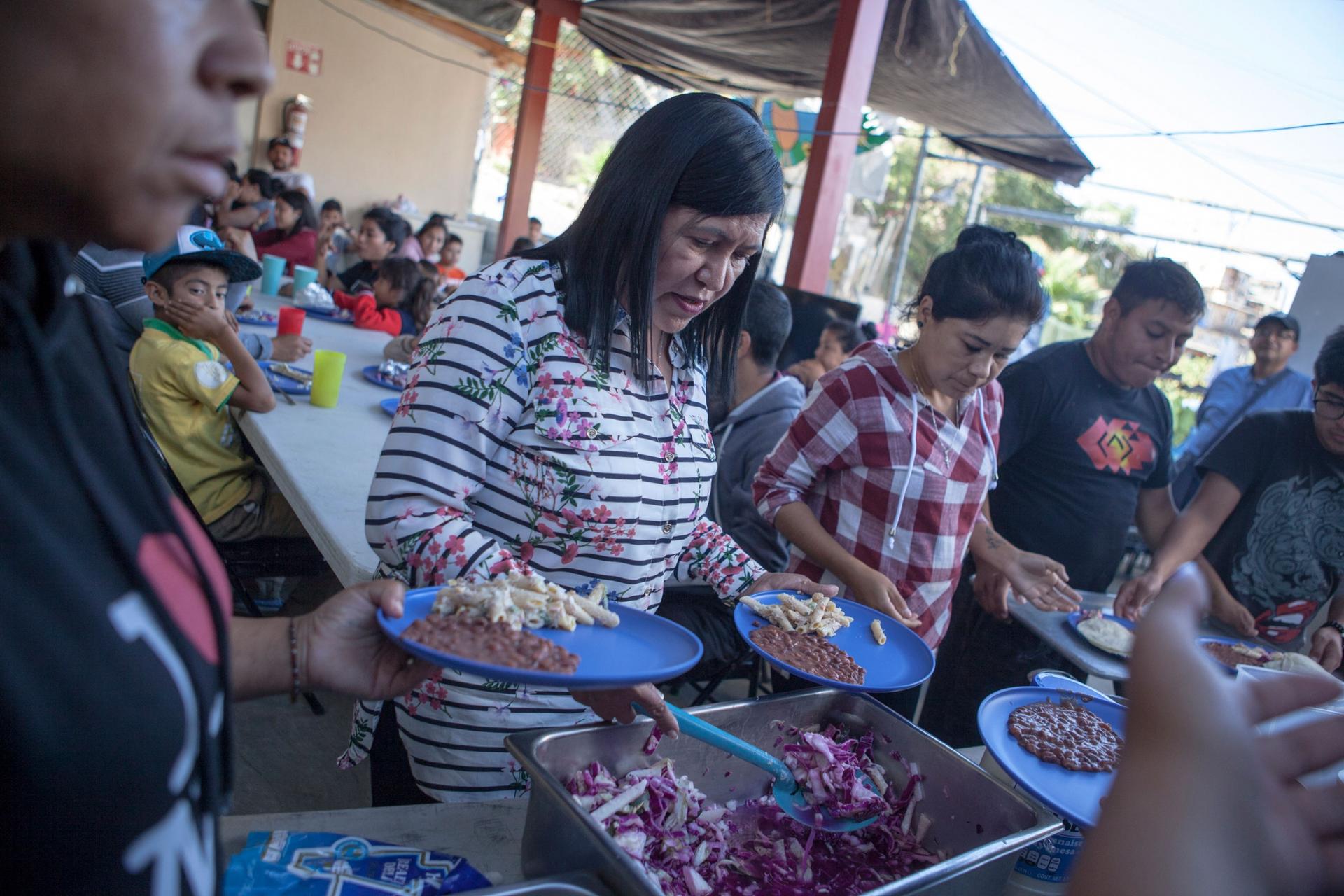 Families wait in line are shown in a serving line where several dishes are available in larger serving containers.