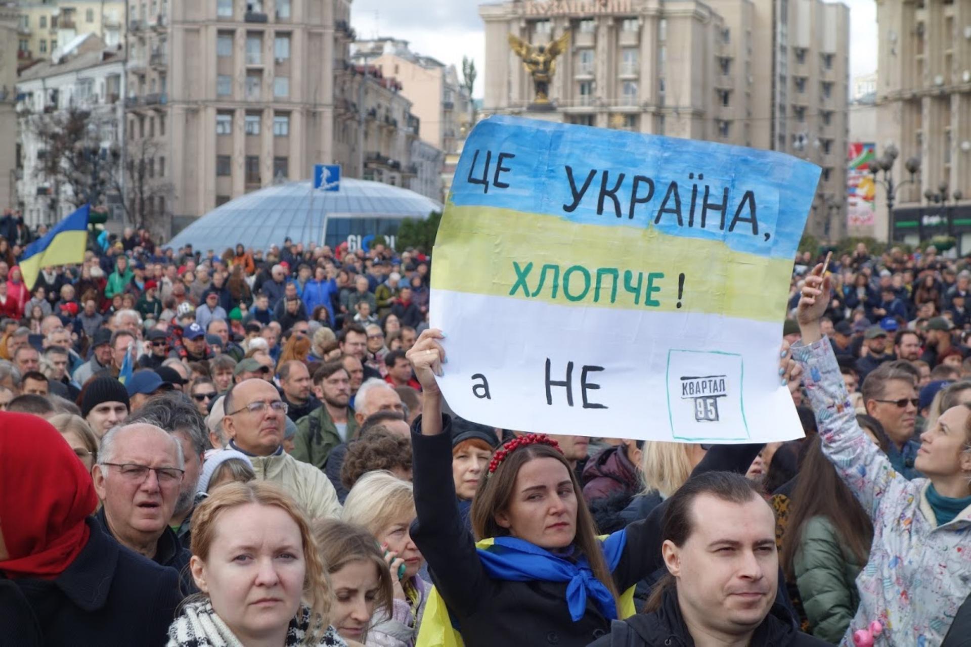 A protester holds a hand-written sign to call out Ukrainian President Volodymyr Zelenskiy during a protest.