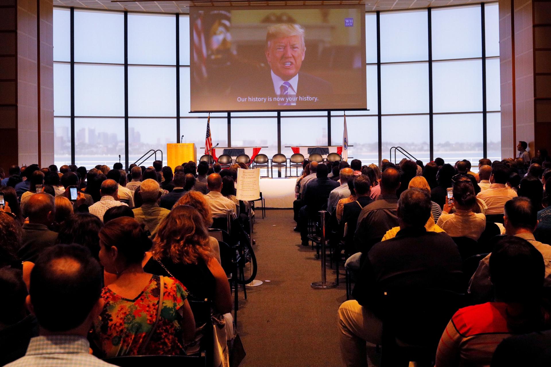 A welcome statement from US President Donald Trump is played after a citizenship ceremony at the John F. Kennedy Presidential Library in Boston, Massachusetts, on July 18, 2018.