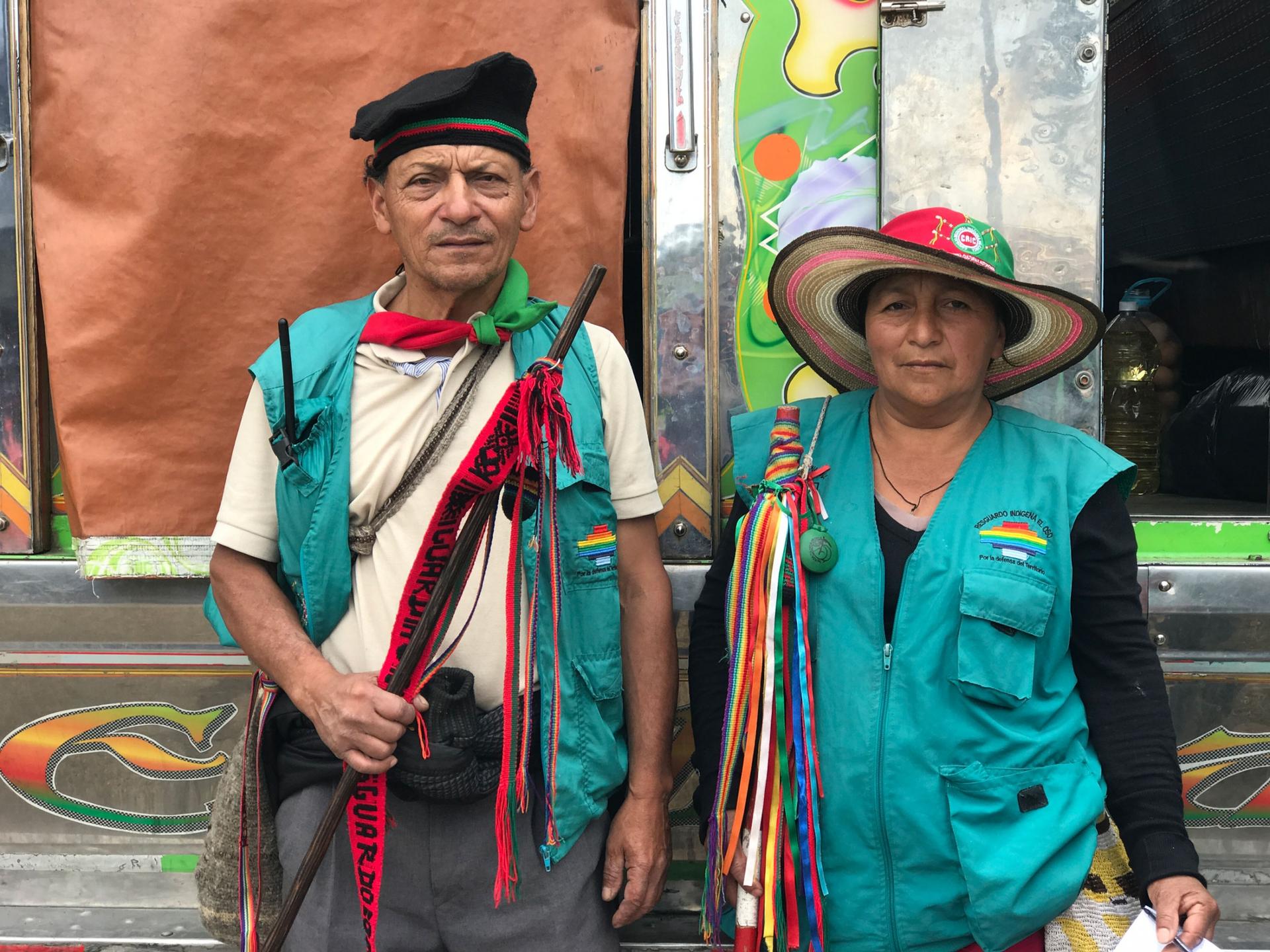 An older Indigenous couple is shown both wearing green vests.