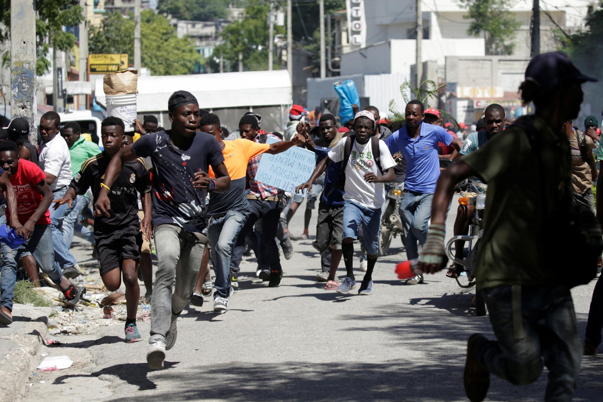 A large group of protesters are shown running in the street.