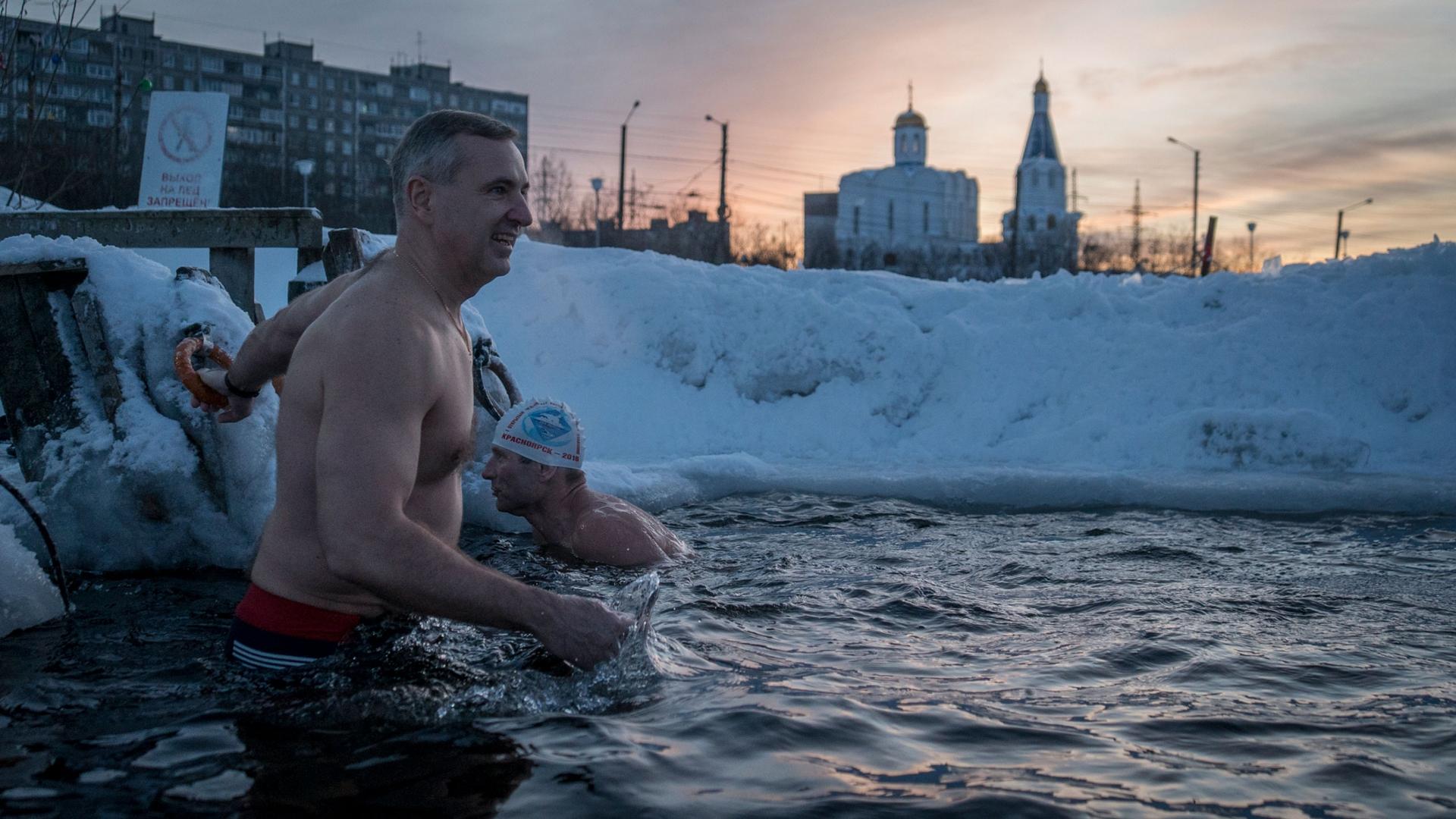 Alexander Spinul is shown without his shirt on and swims in an ice hole.
