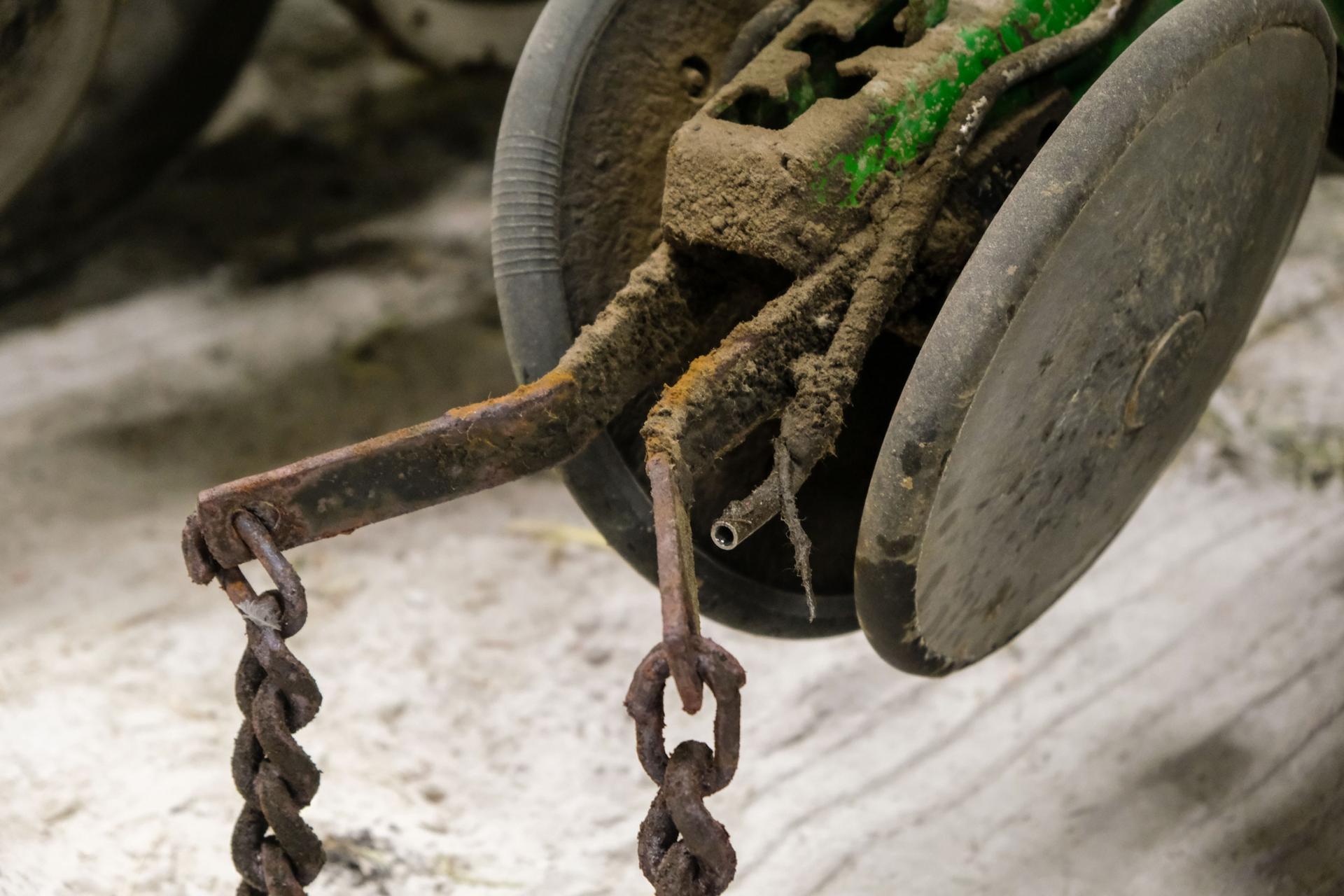 A wheel is shown with rusted metal chains attached and a small tube is connected.