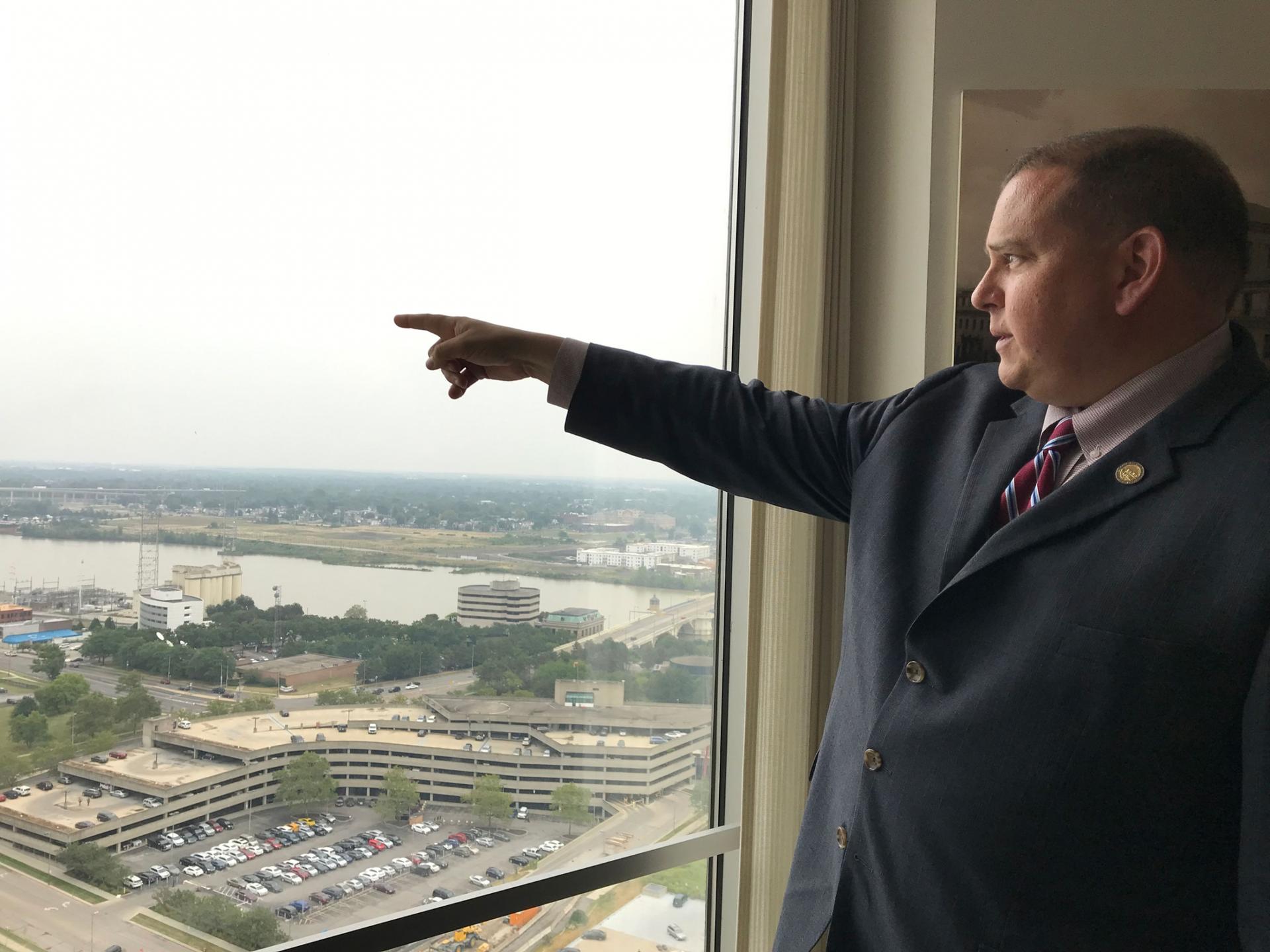 Toledo Mayor Wade Kapszukiewicz is shown wearing a dark suit standing at a window point out.