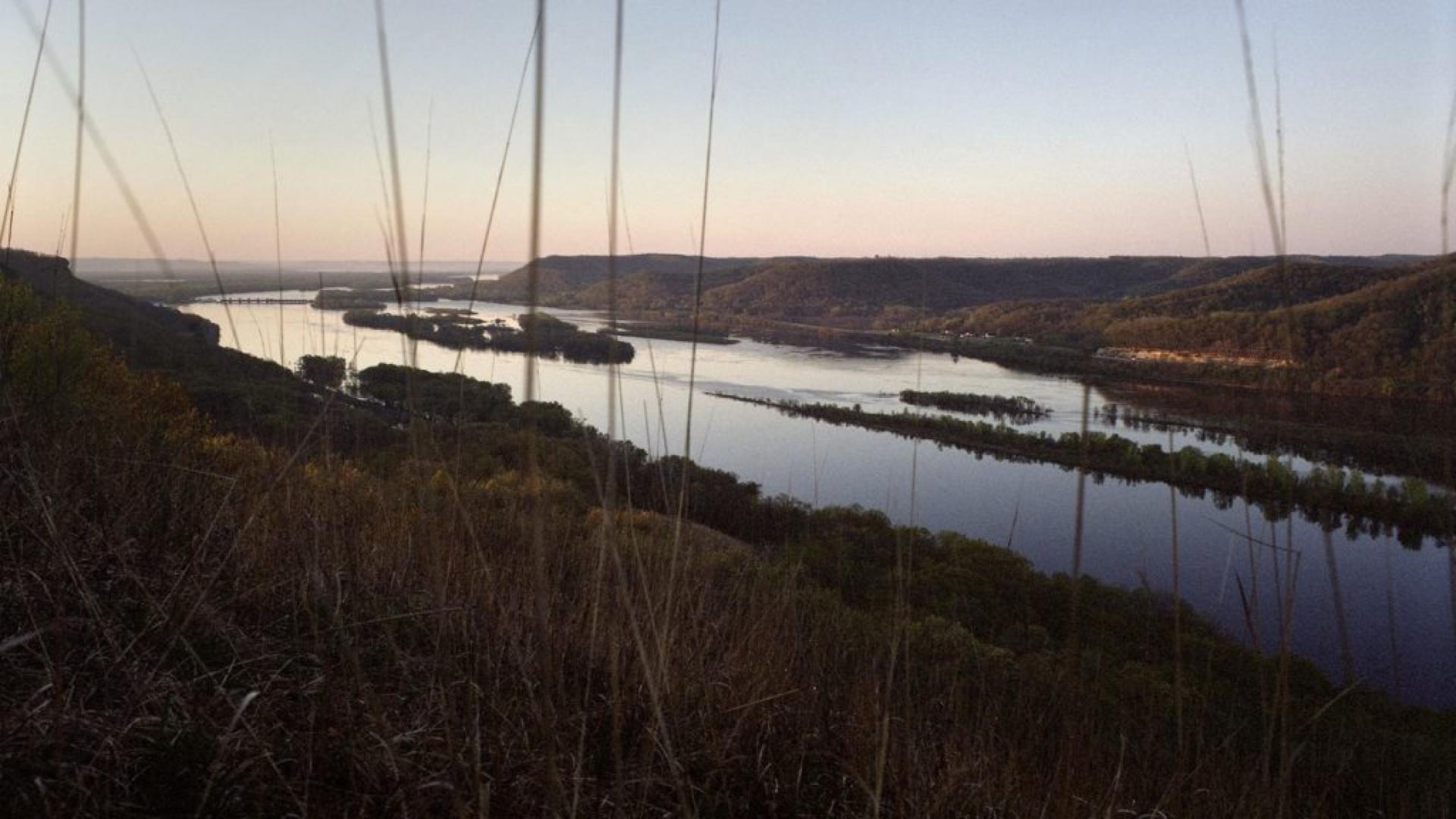 The Mississippi River is shown in the distance flowing through landscape of trees and grass.