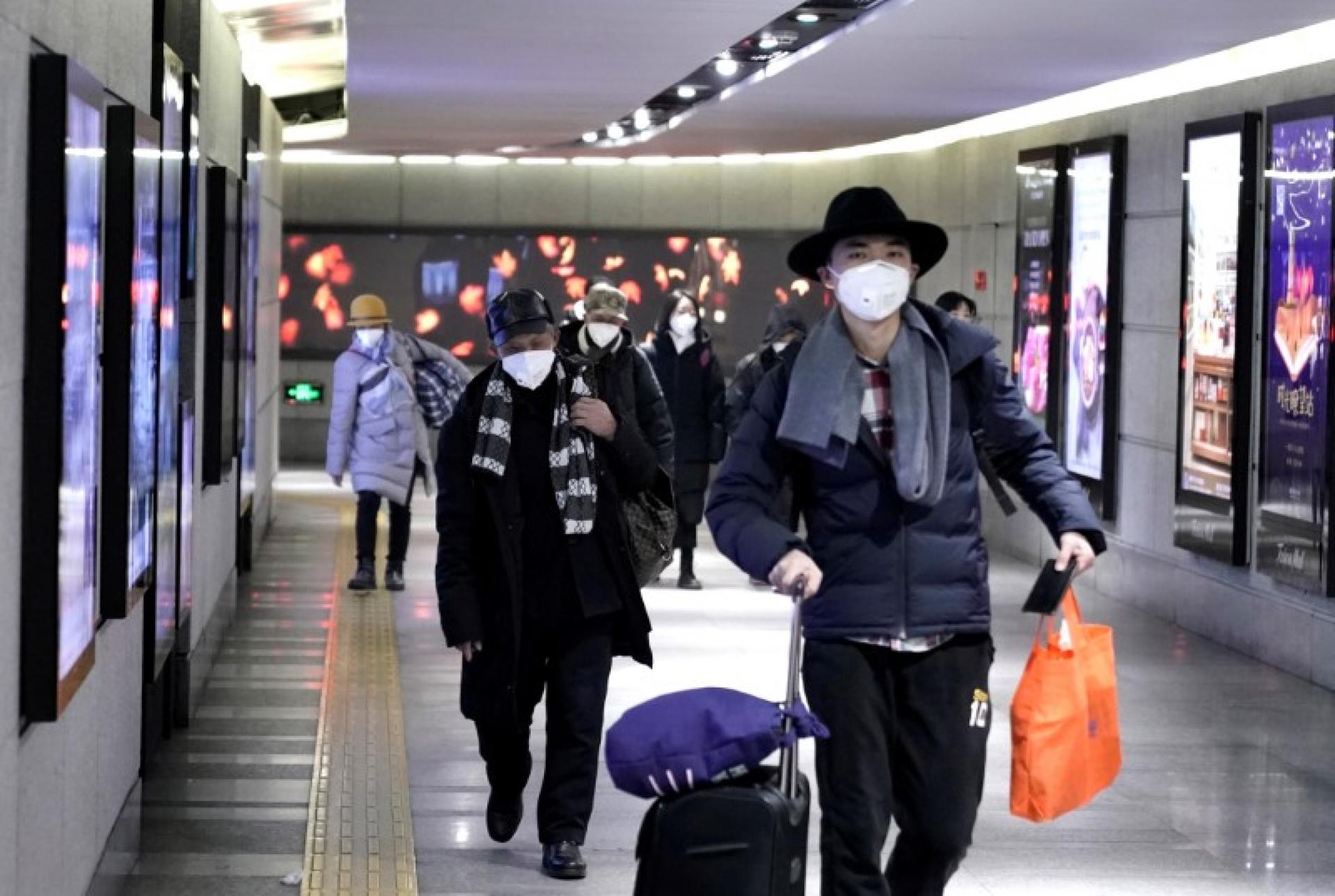 People wearing masks walk through an underground passage to the subway in Beijing, Jan. 21, 2020. 