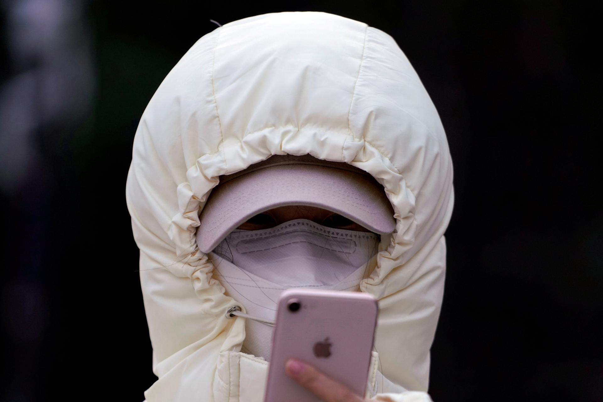 A woman wearing a mask checks her mobile phone in Shanghai, Jan. 29, 2020. 