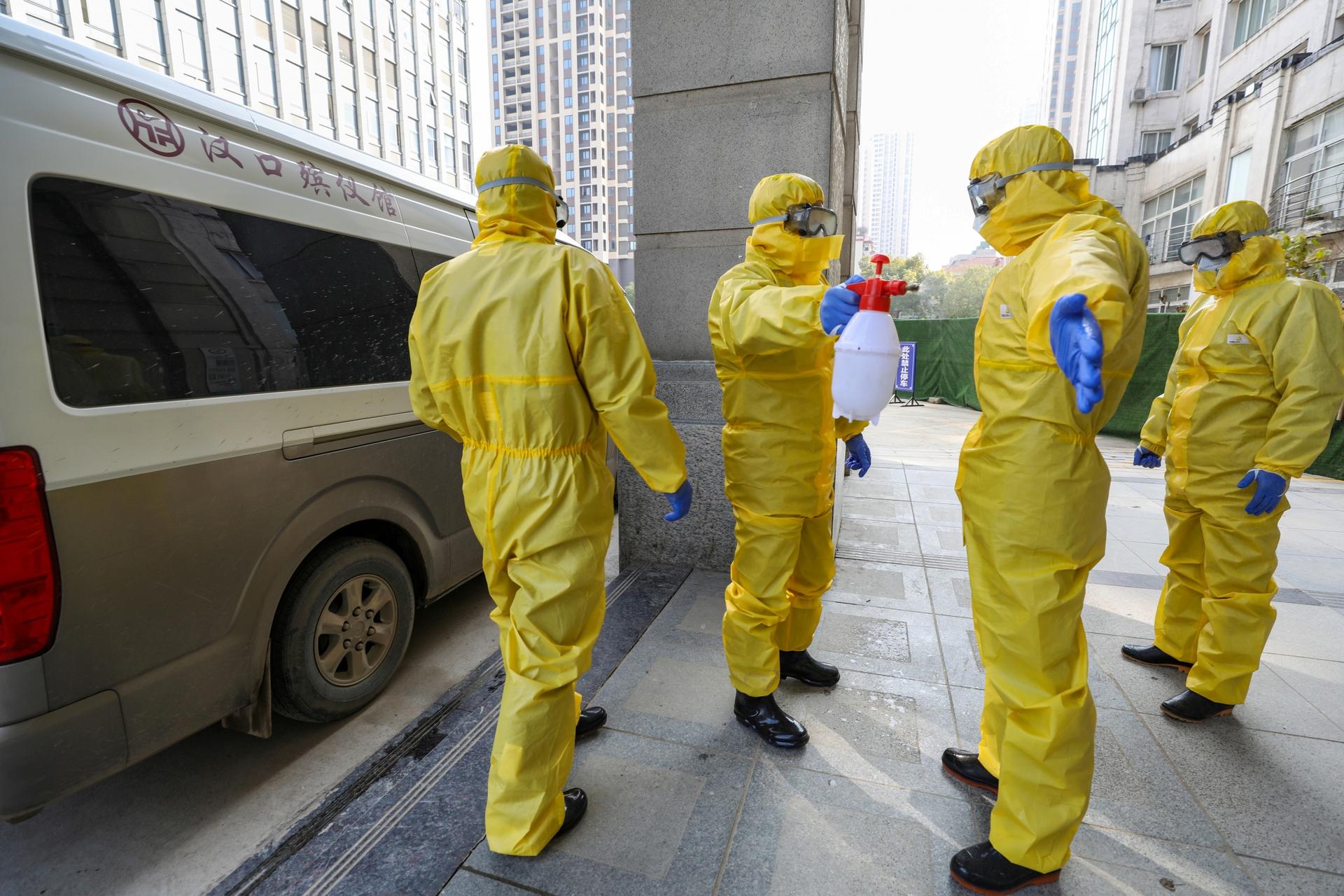 Funeral parlor staff members in protective suits help a colleague with disinfection after they transferred a body at a hospital, following the outbreak of a new coronavirus in Wuhan, Hubei province, China, Jan. 30, 2020. 
