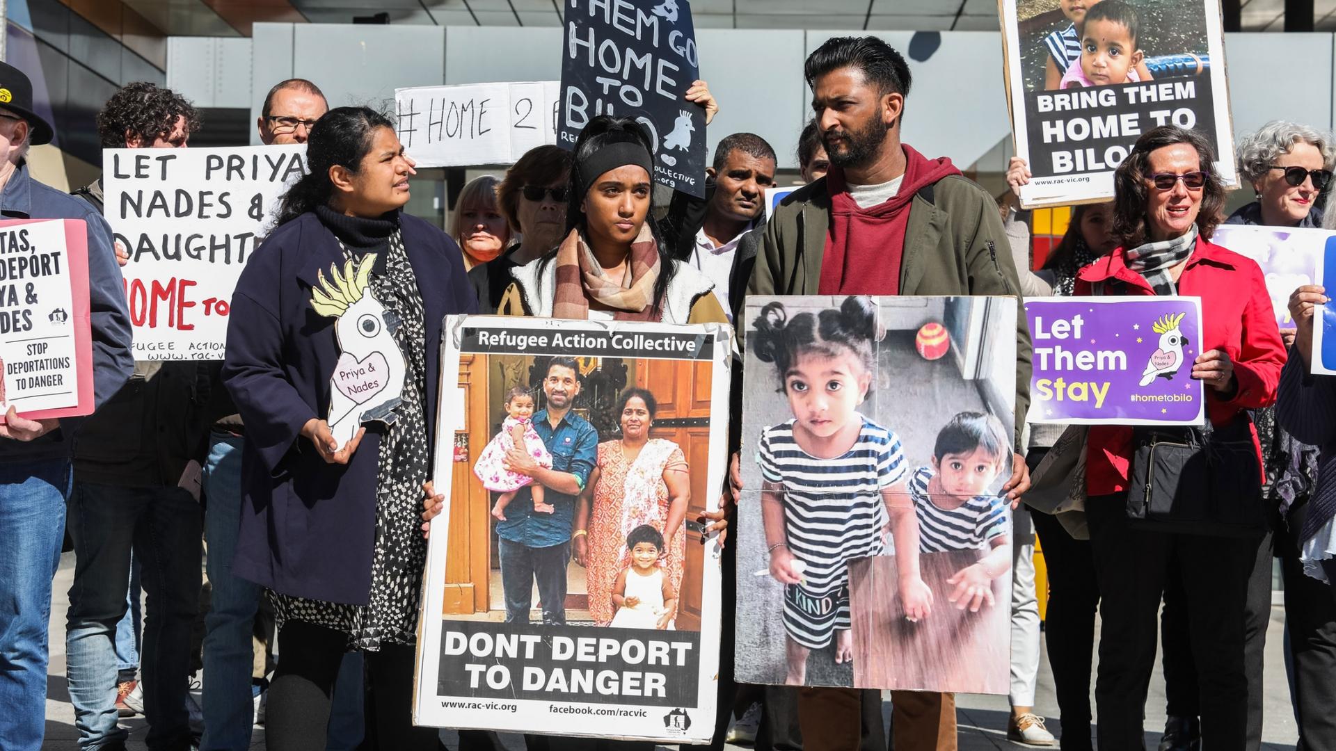 A group of protesters are shown holding placards with pictures of a Tamil family that includes the father, mother and their two small children.
