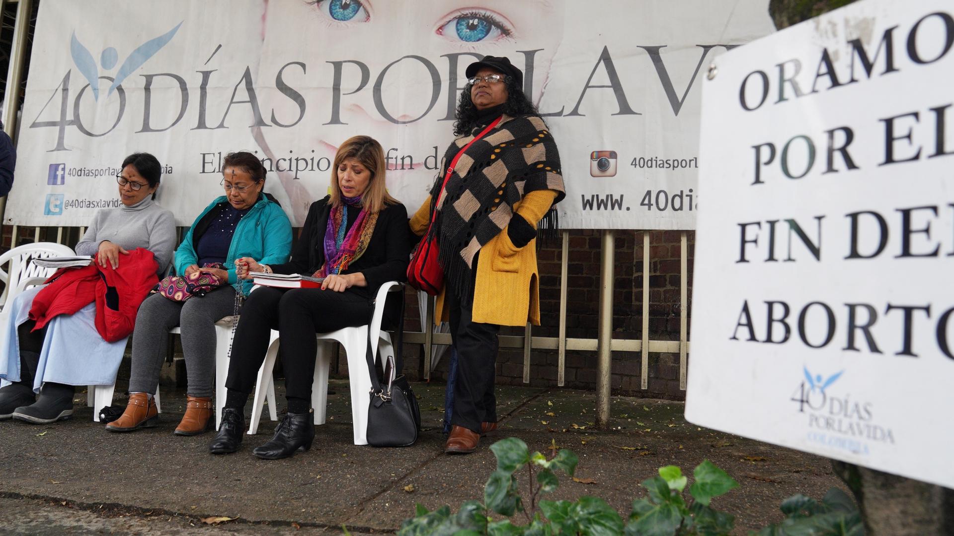 Four women pray outside at an anti-abortion vigil.