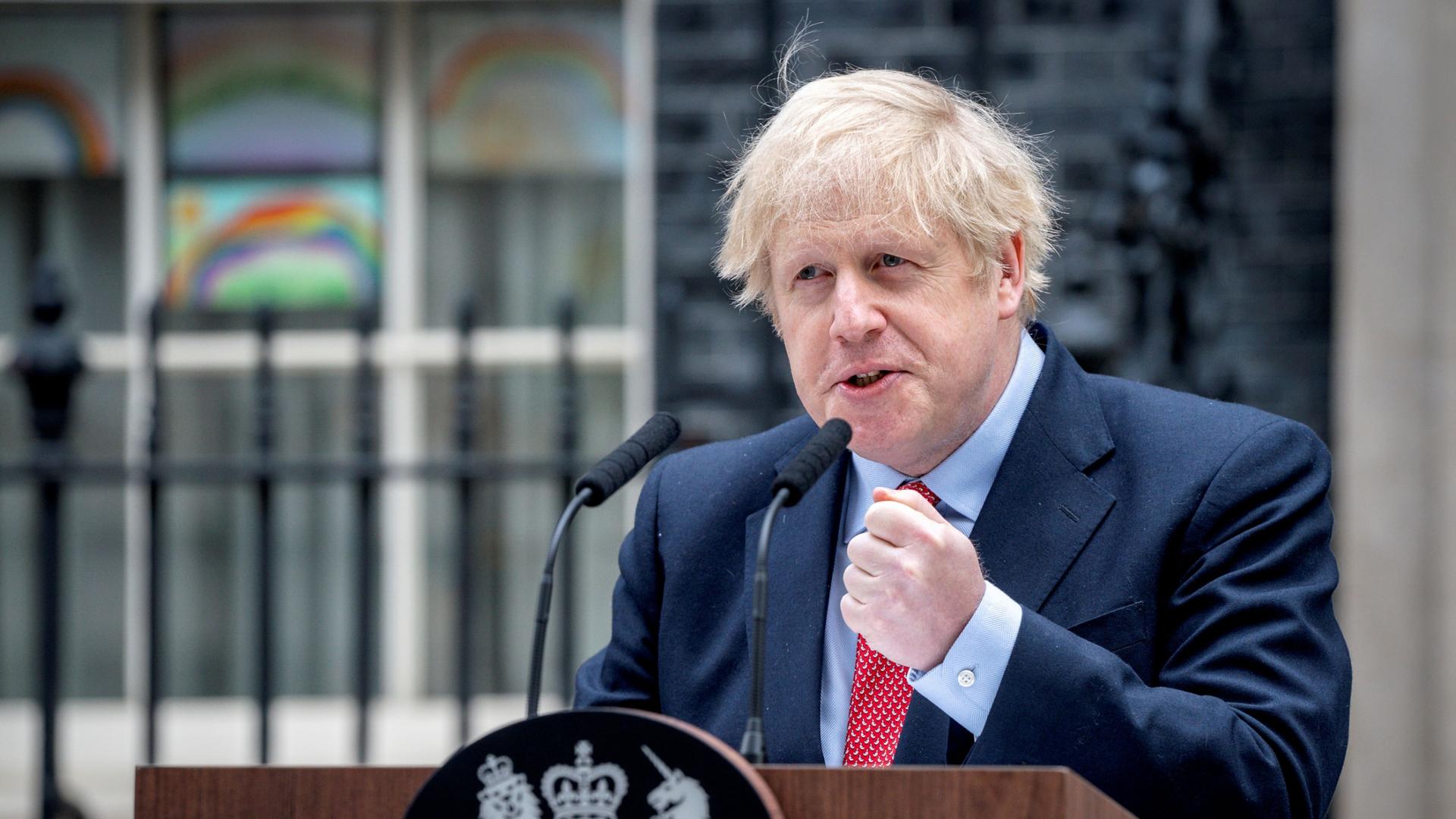 Britain's Prime Minister Boris Johnson is shown speaking from a wooden podium with his fist raised and clenched.