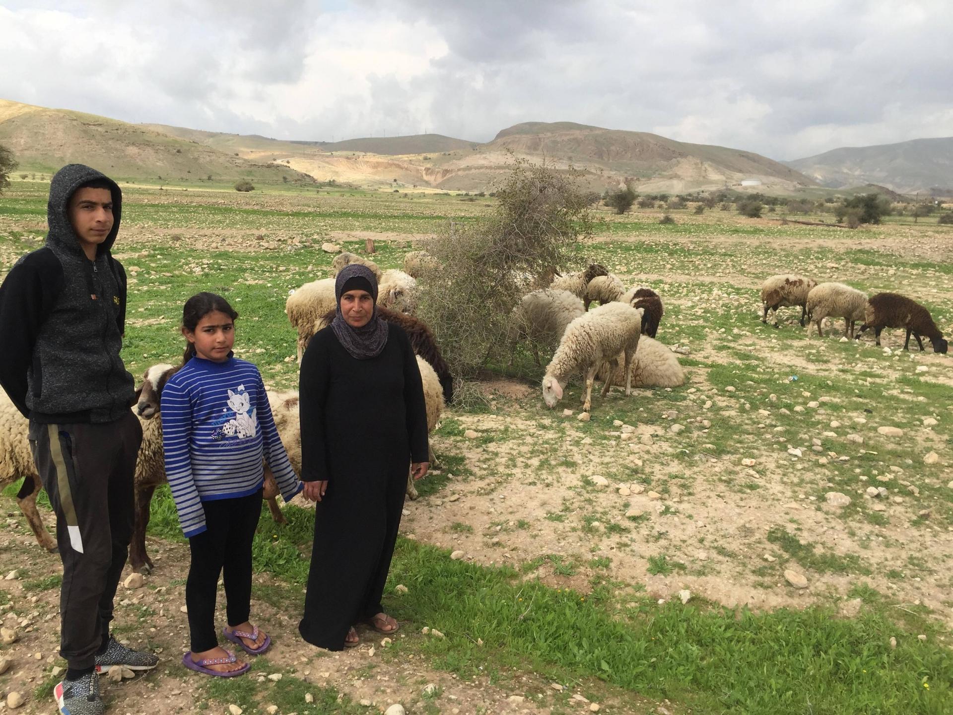 Iyad Ebbayat, left, his younger sister, and his mother, Noor Ebbayat with their sheep in the Palestinian village of Fasayil. 