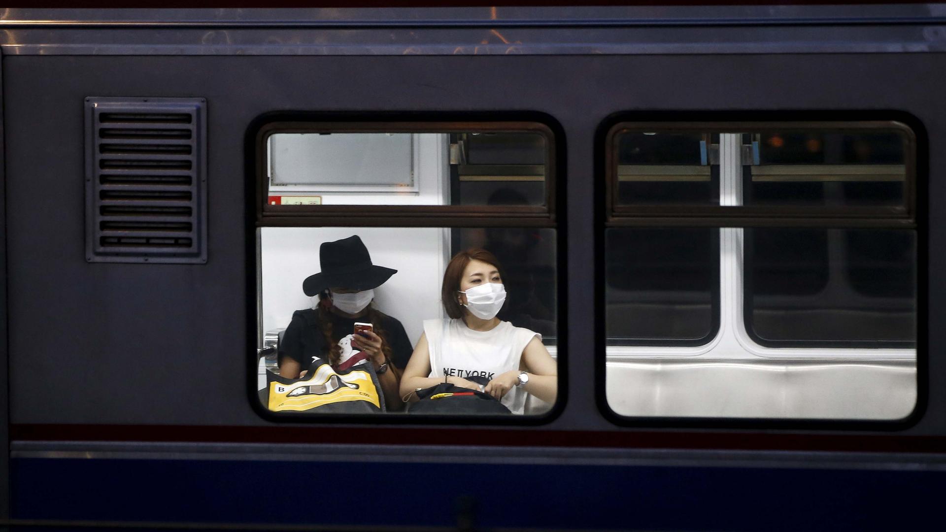 Women wearing masks to prevent contracting Middle East Respiratory Syndrome (MERS) ride a subway train in Seoul, South Korea, on June 12, 2015.