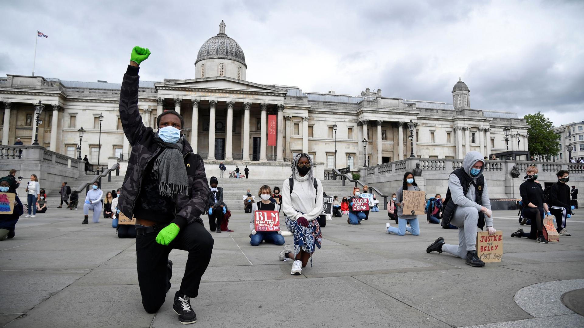 A large group of people are shown kneeling while spaced apart from each other in Trafalgar Square.