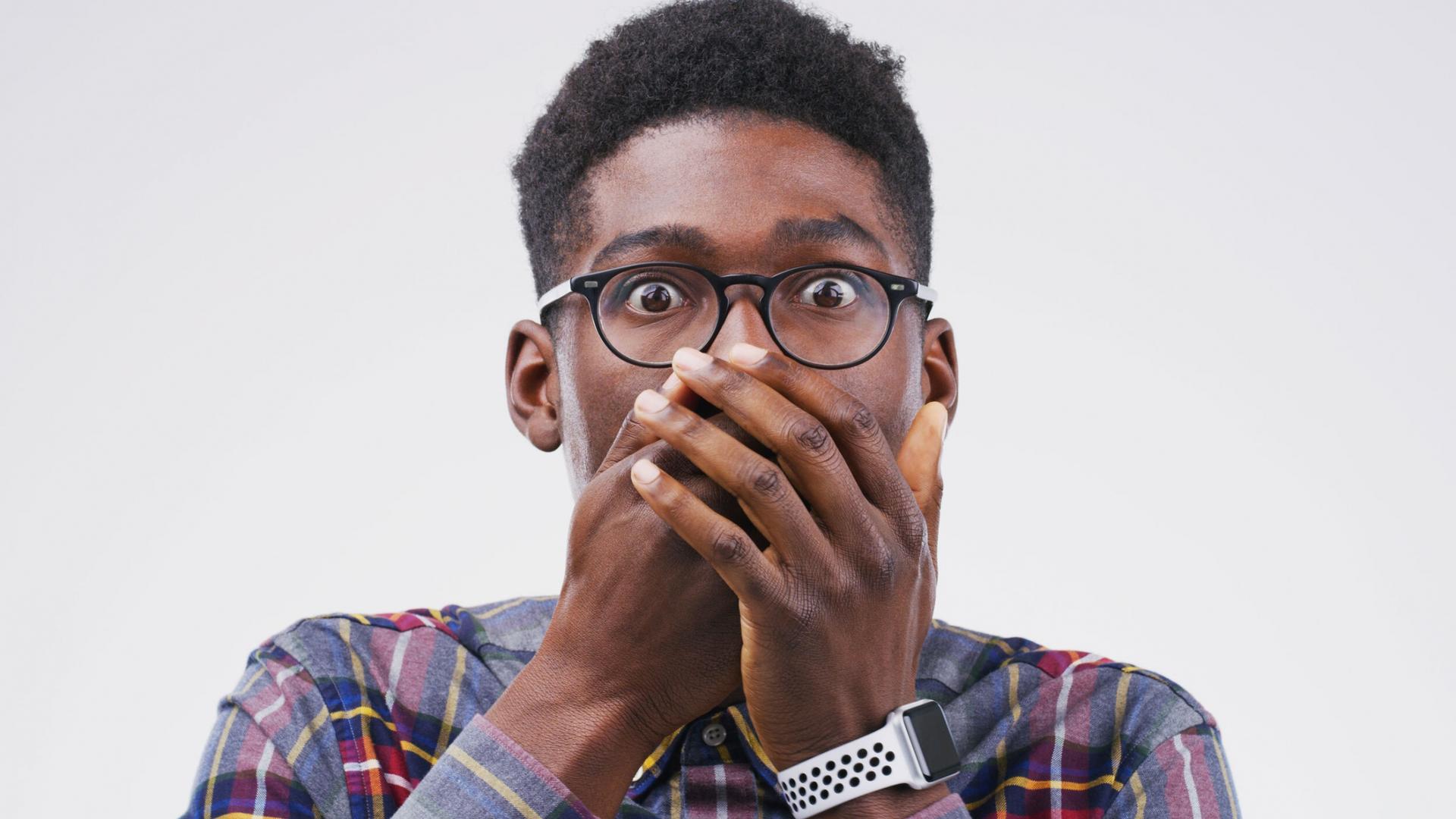A man poses for the camera with his hands over his mouth in this stock photo