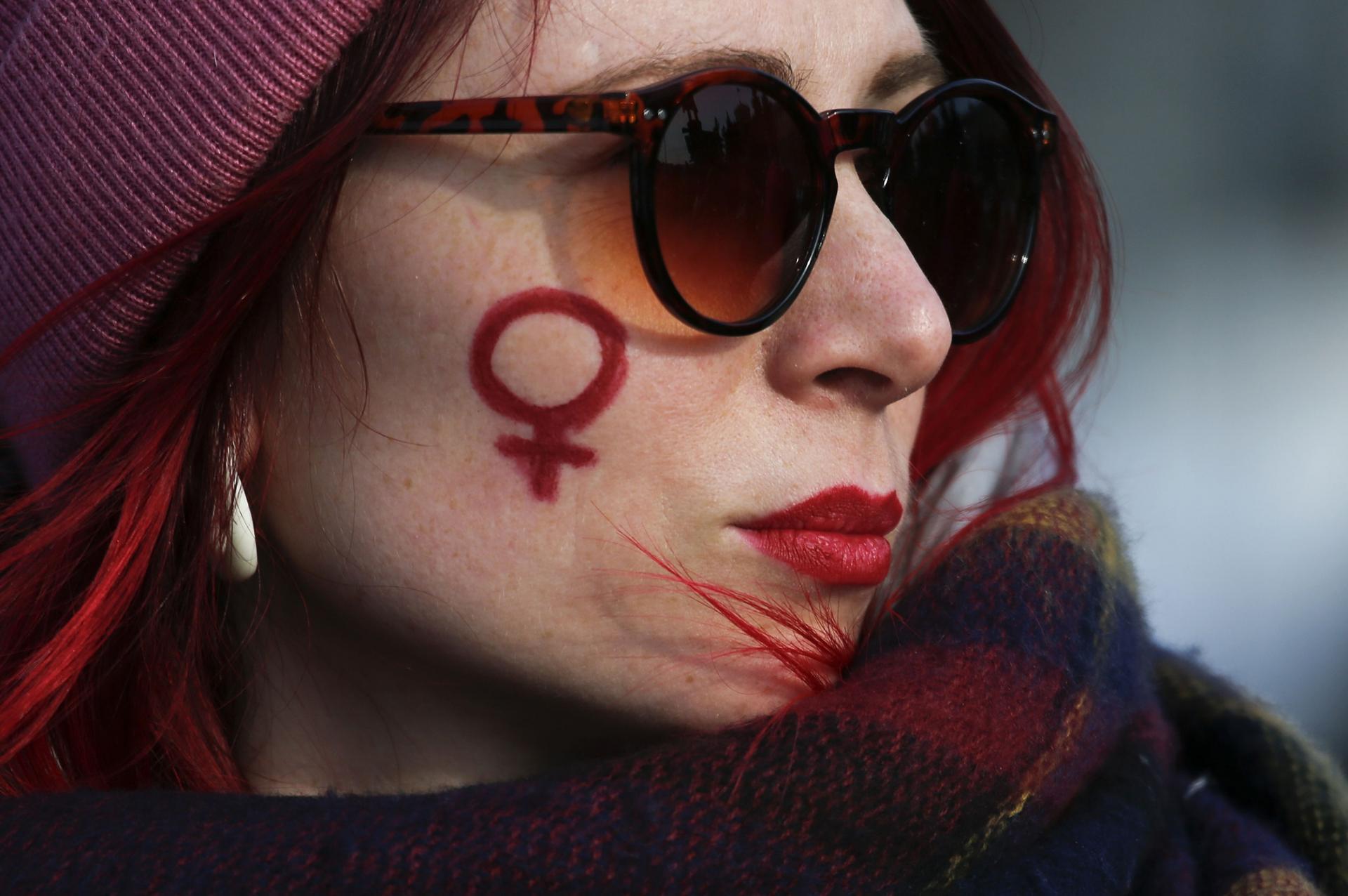 A woman has drawn the symbol for women on her cheek