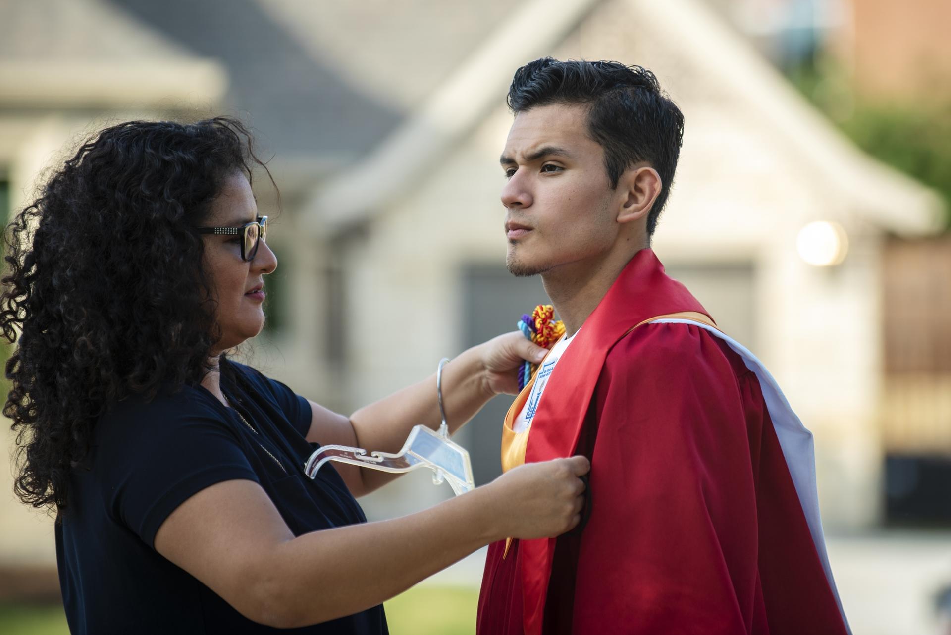 Xochitl Ortiz, left, helps her son Izcan Ordaz to try on his graduation gown outside their home in Keller, Texas, May 28, 2020.