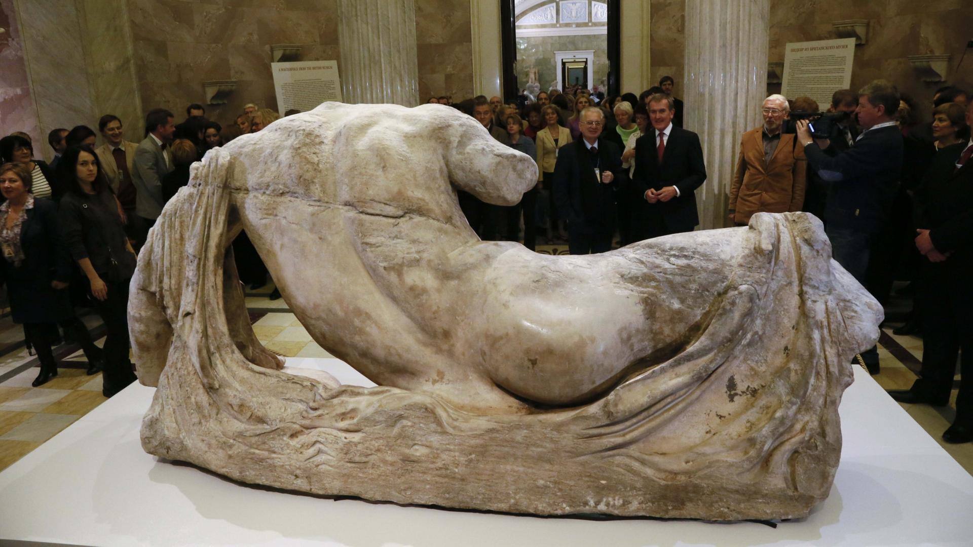 Onlookers attend the opening of the exhibition on Greek art with the marble sculpture of the river god Ilissos, in front, in the Hermitage in St. Petersburg, Russia, Dec. 5, 2014.