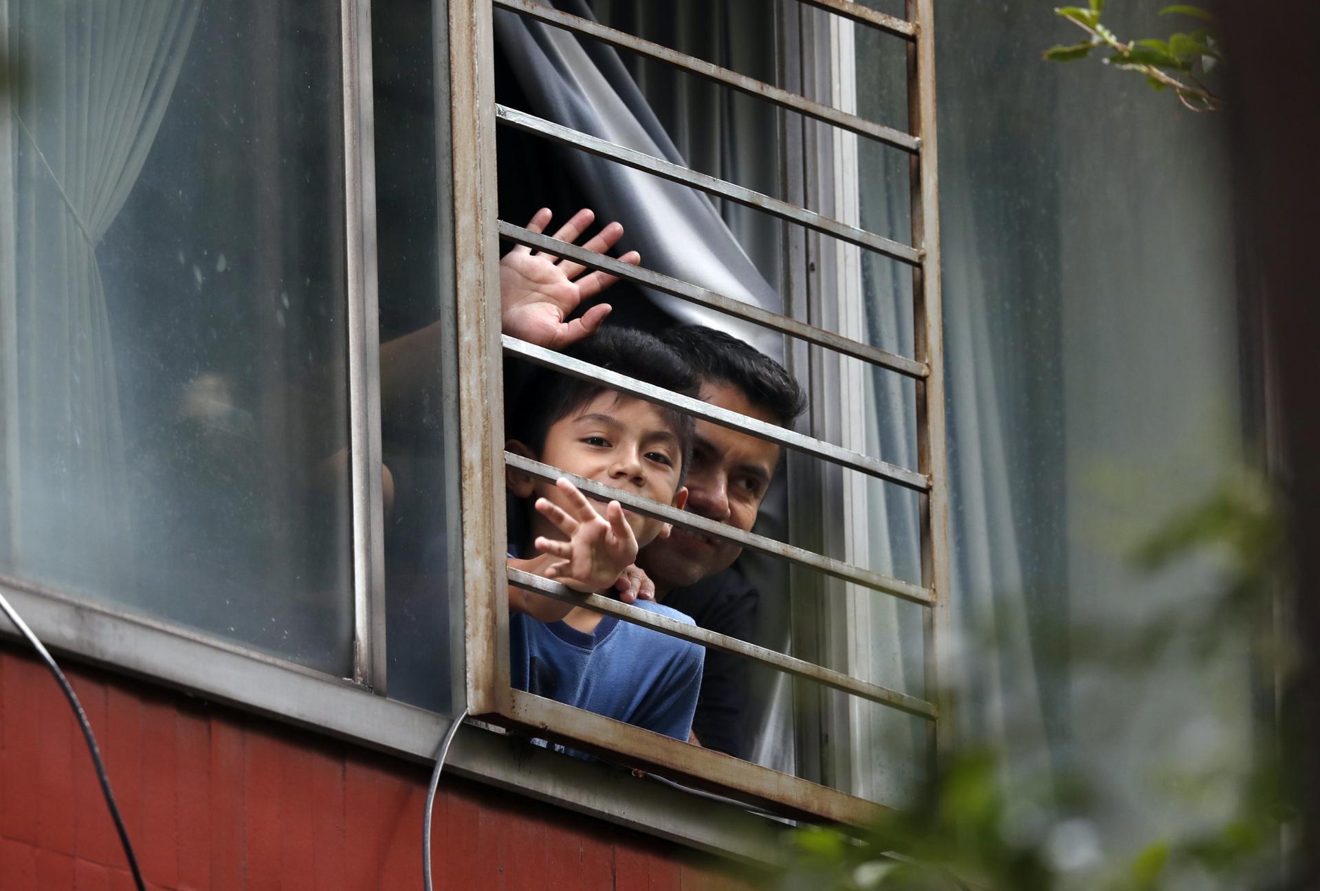 Residents wave from an apartment as Percibald García reads children's books aloud outside the high-rise buildings in the Tlatelolco housing complex, in Mexico City, Mexico, on July 18, 2020.