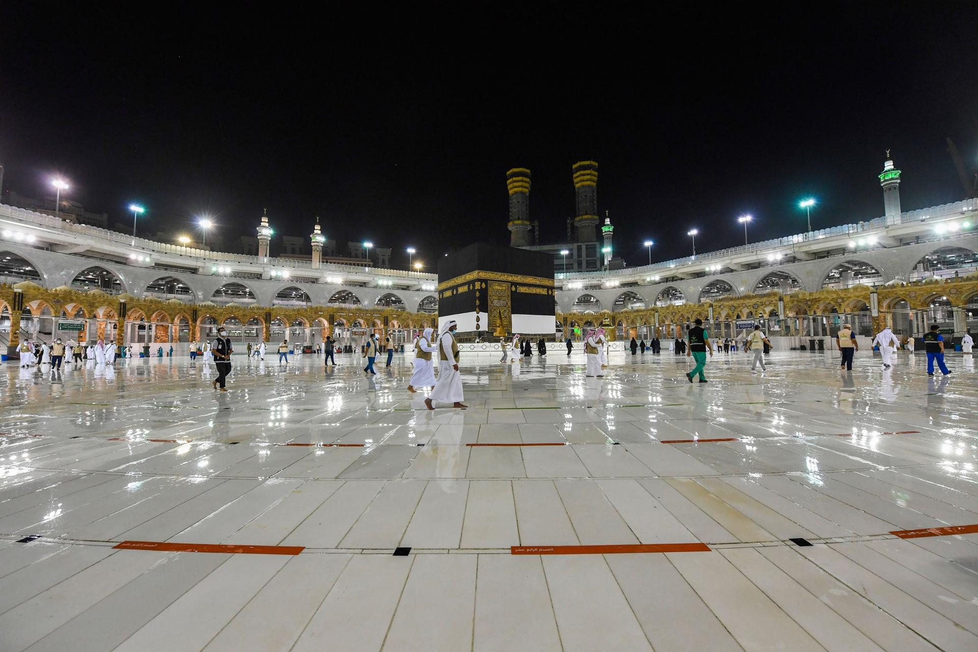 Workers make preparations for the hajj with lights on around the facility showing a shiny floor.