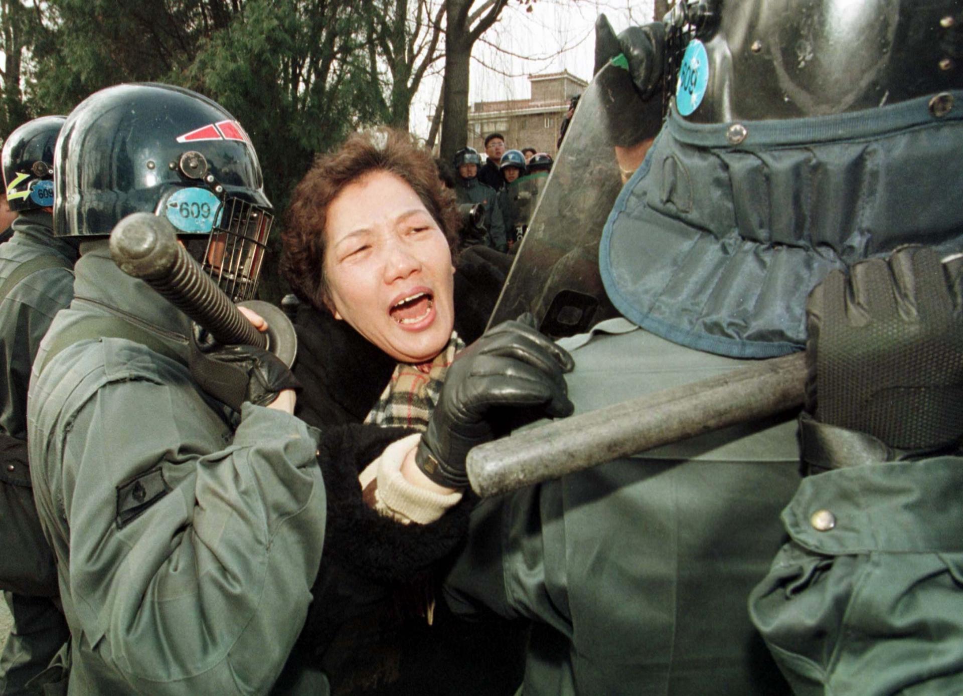 A woman protester cries out amid riot police in green uniforms. 