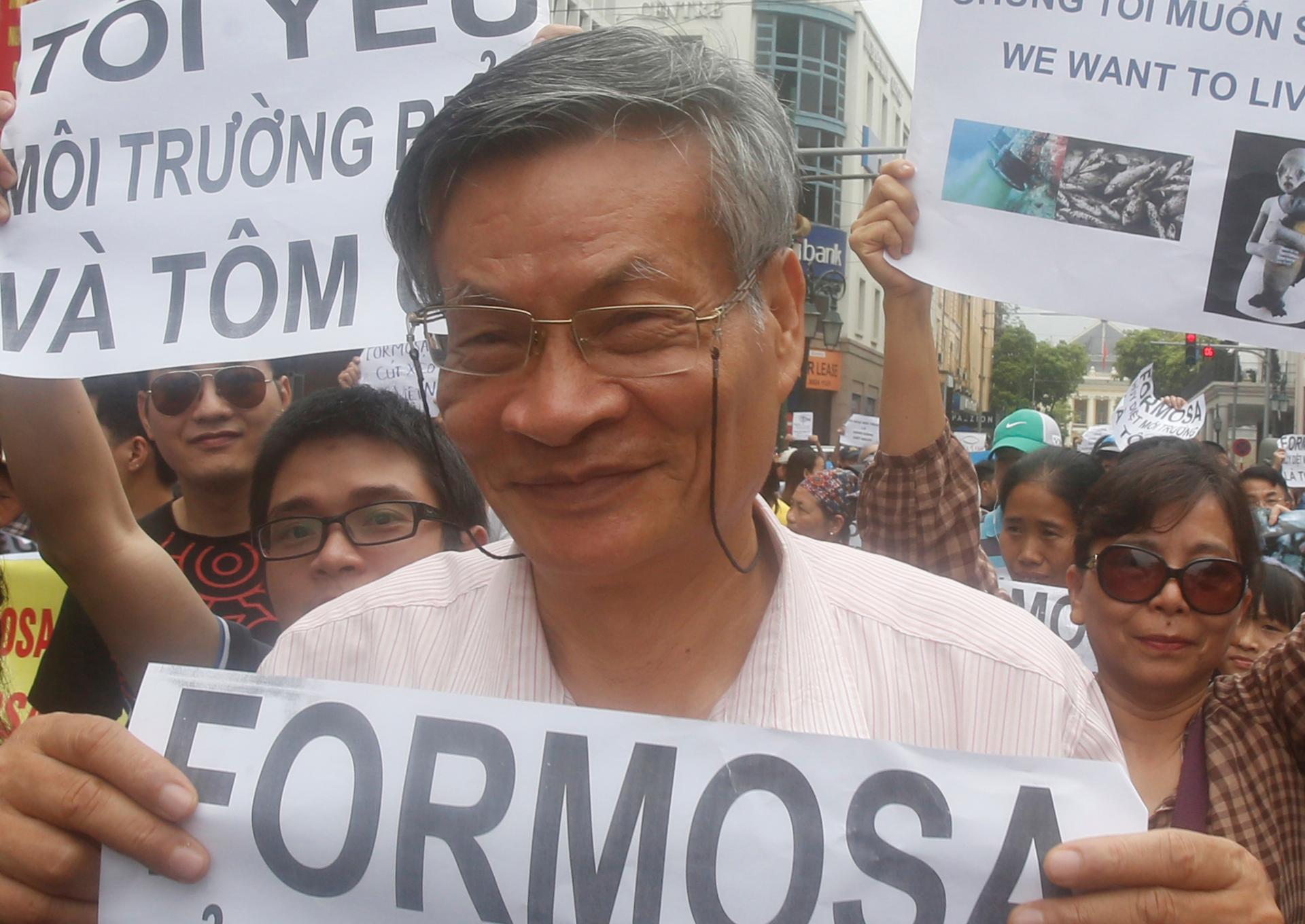 A man holds a protest sign in a large crowd against Formosa Plastics 