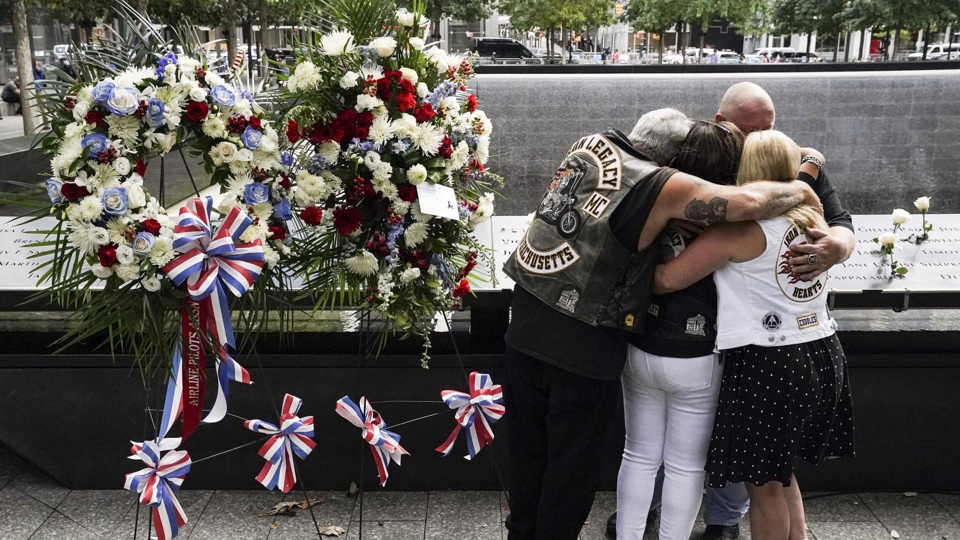 Mourners hug beside the names of the deceased Jesus Sanchez and Marianne MacFarlane at the National September 11 Memorial and Museum, Sept. 11, 2020, in New York.